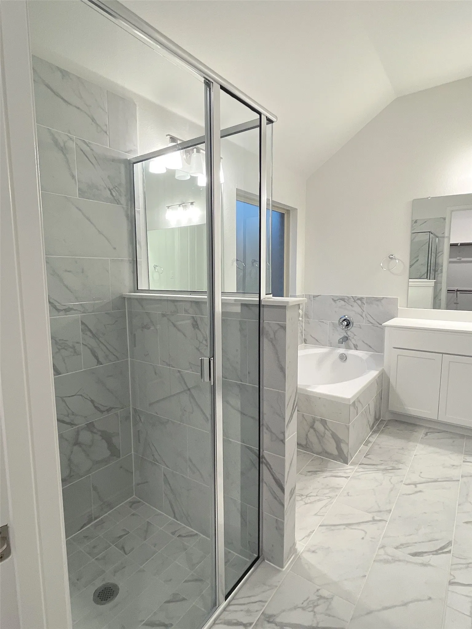 Bathroom featuring marble finish floor, vaulted ceiling, a shower stall, and a bath