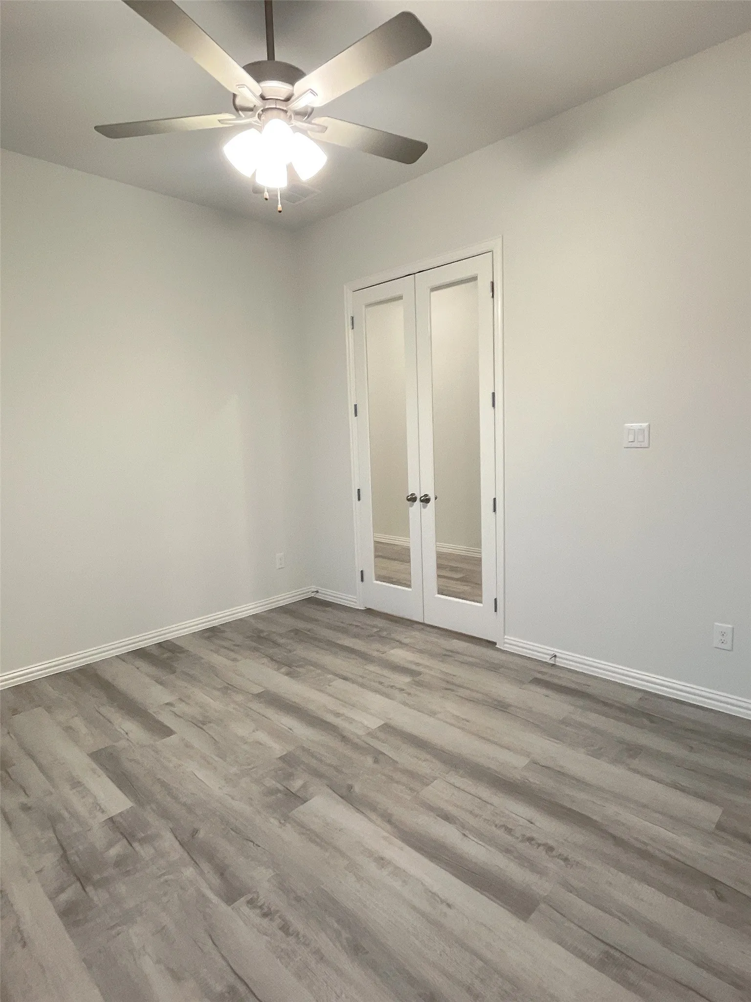 Unfurnished room with french doors, a ceiling fan, light wood-style flooring, and baseboards