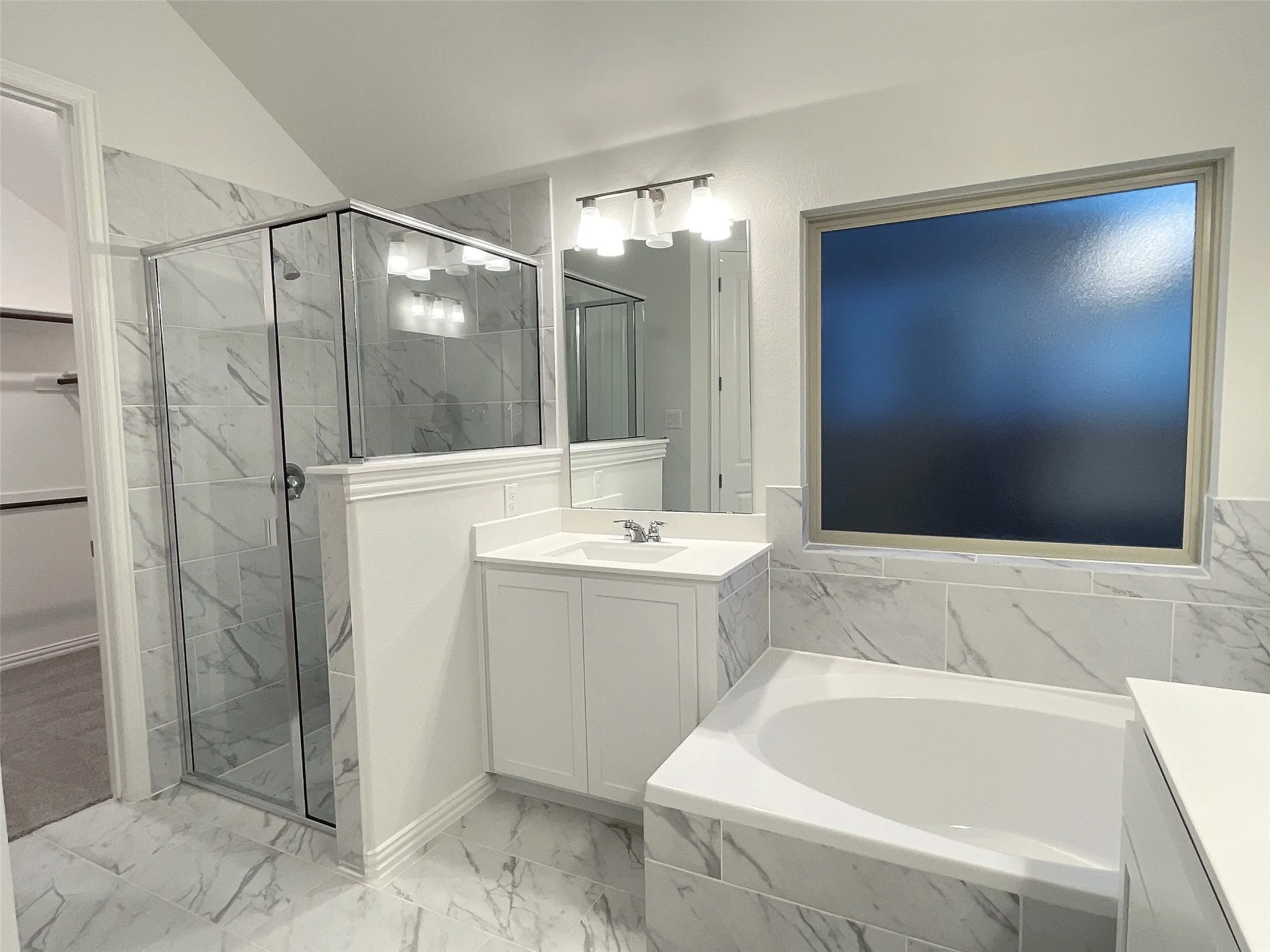 Bathroom with marble finish floor, a garden tub, vanity, and a shower stall