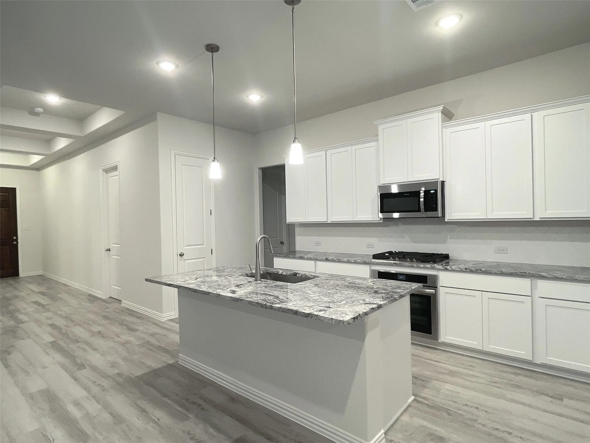 Kitchen with stainless steel appliances, a sink, a center island with sink, and white cabinets