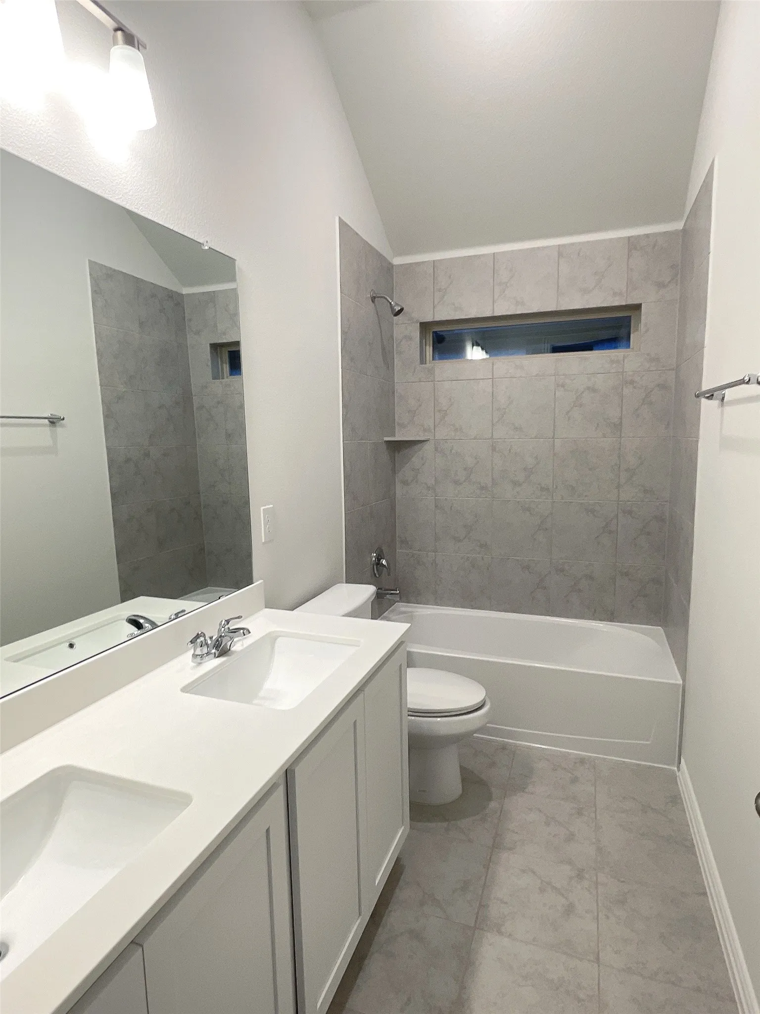 Full bath with lofted ceiling, bathtub / shower combination, a sink, and toilet