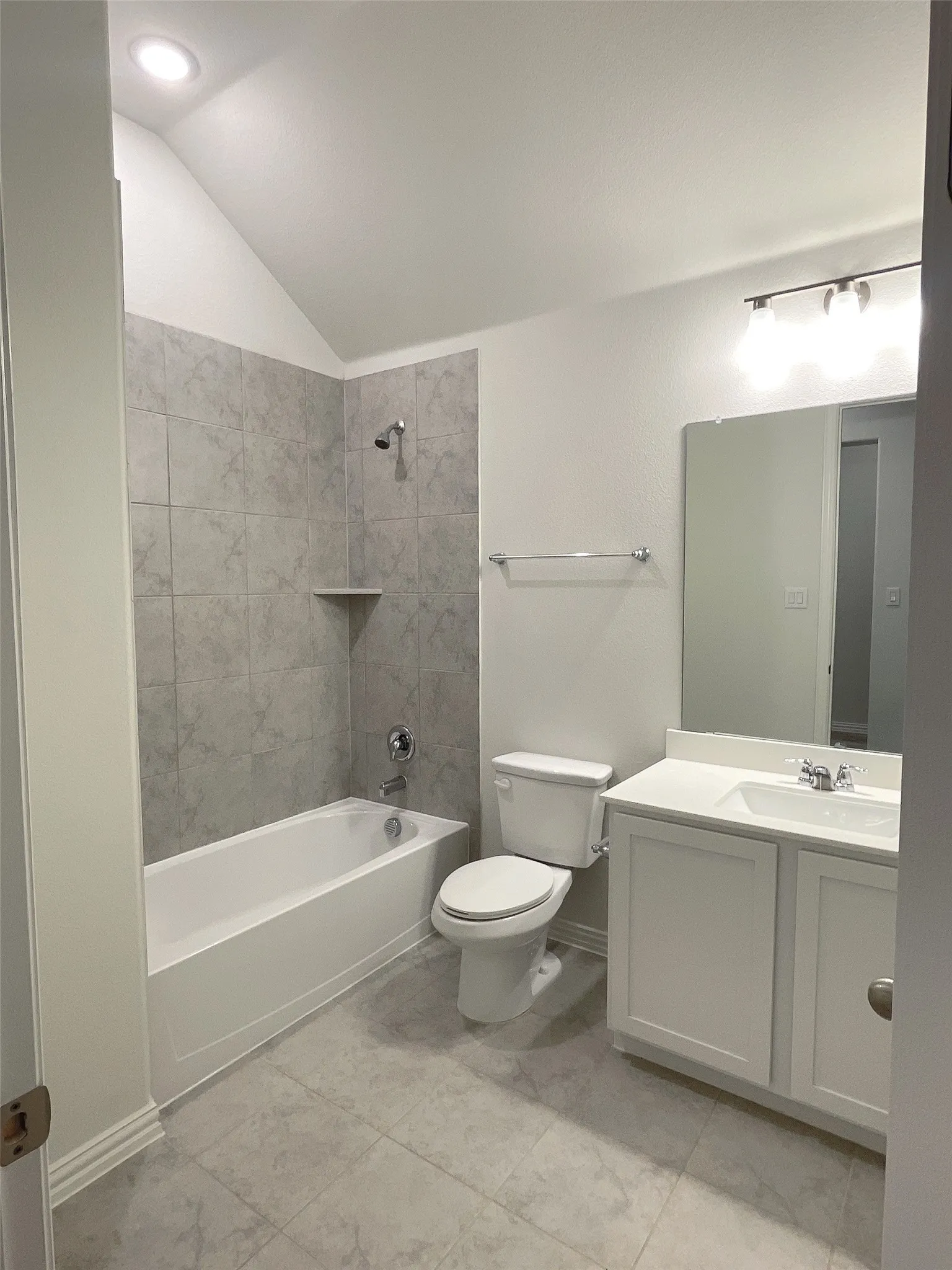 Full bathroom featuring lofted ceiling, bathtub / shower combination, toilet, vanity, and baseboards
