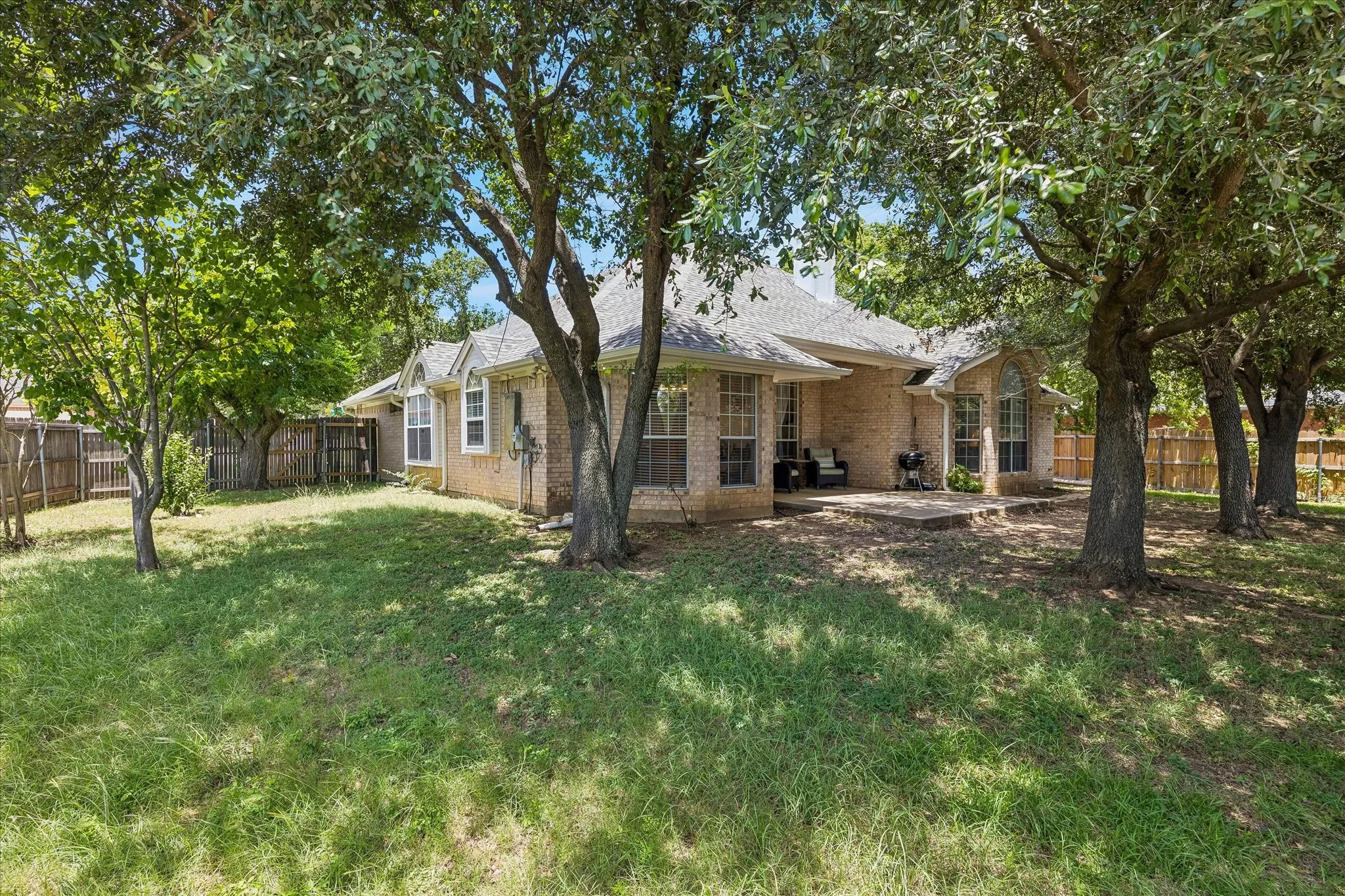 Expansive backyard with mature trees, providing shade all over.