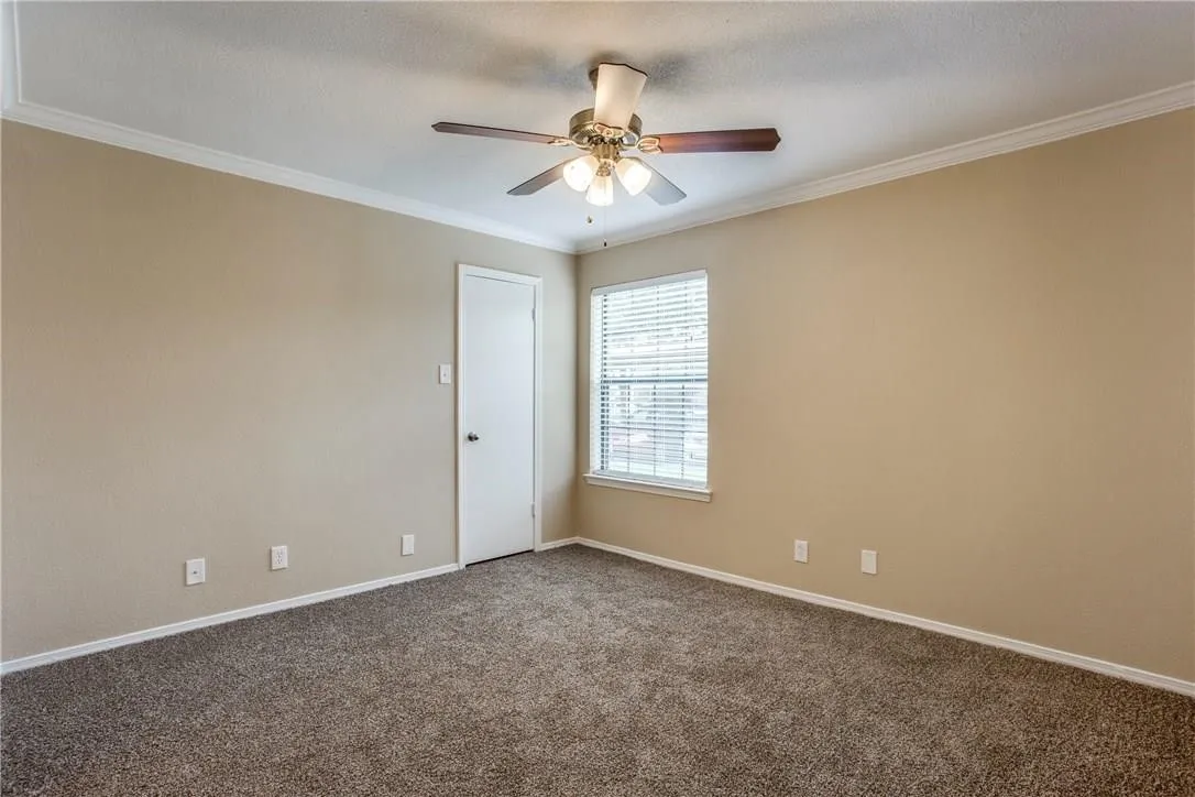 Carpeted empty room featuring ornamental molding and ceiling fan