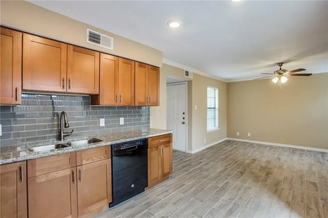 Kitchen with black dishwasher, tasteful backsplash, sink, light wood-type flooring, and ceiling fan