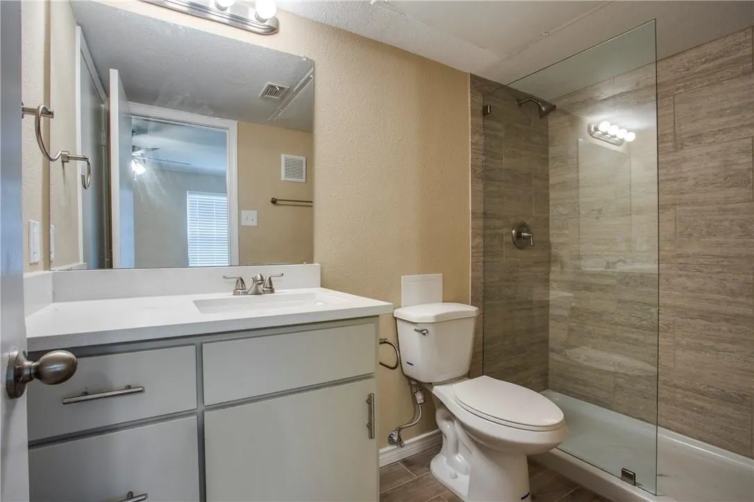 Bathroom featuring vanity, a shower with shower door, toilet, and tile patterned floors