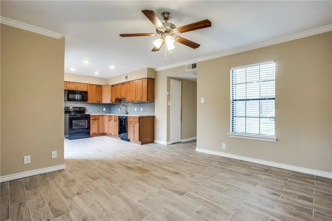 Kitchen with crown molding, tasteful backsplash, ceiling fan, black appliances, and sink