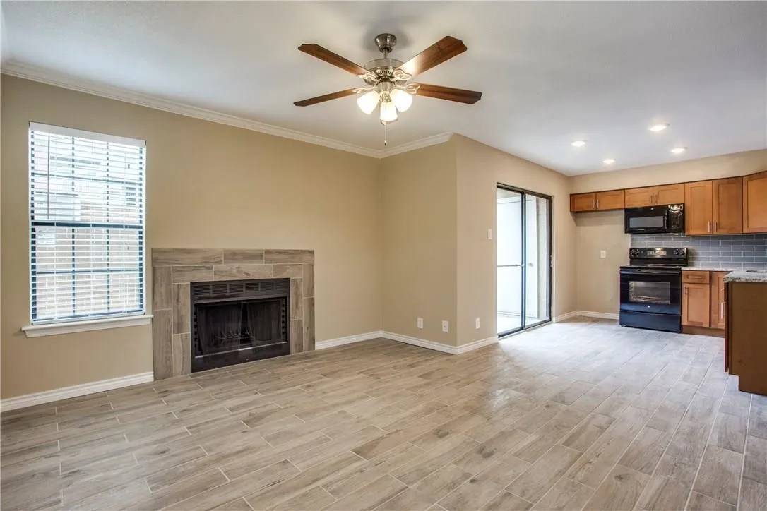 Unfurnished living room with a healthy amount of sunlight, a tile fireplace, ornamental molding, and ceiling fan