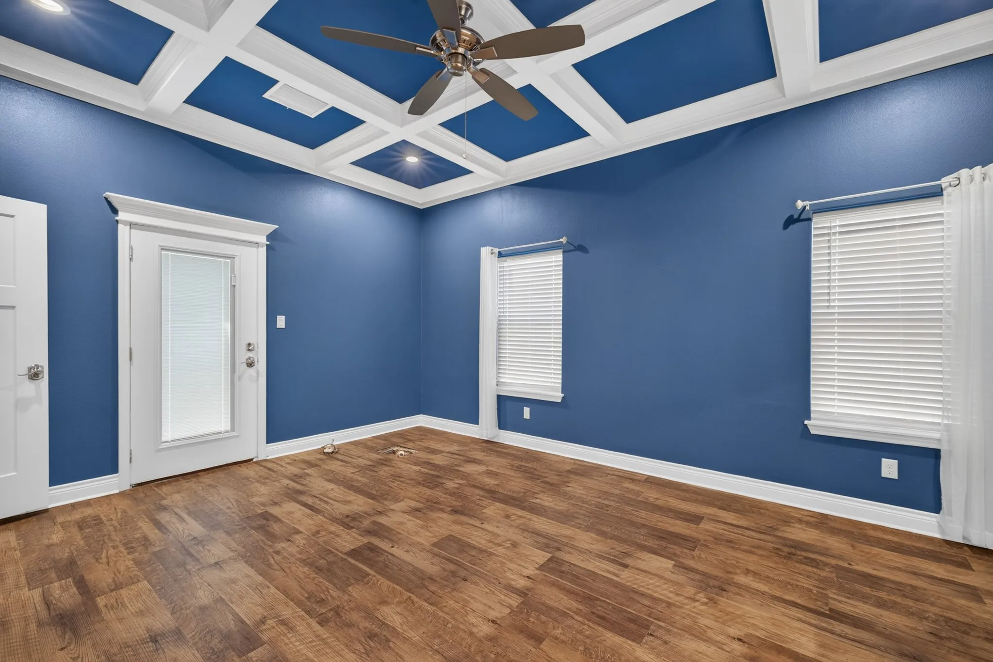 Coffered ceiling with recessed lighting, wood-finish flooring, ceiling fan, and two windows with blinds