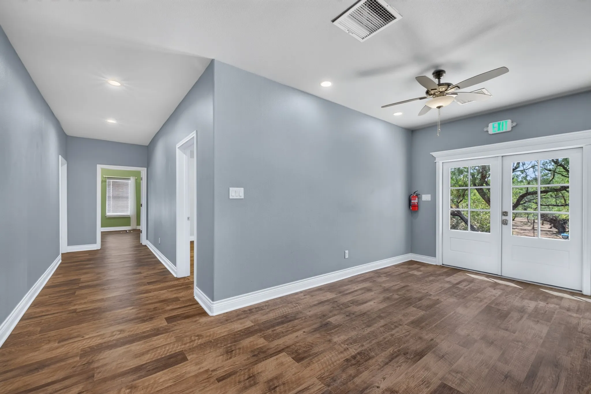 Wood-finish flooring throughout, recessed ceiling lighting, ceiling fan light fixture, and double glass-paneled doors