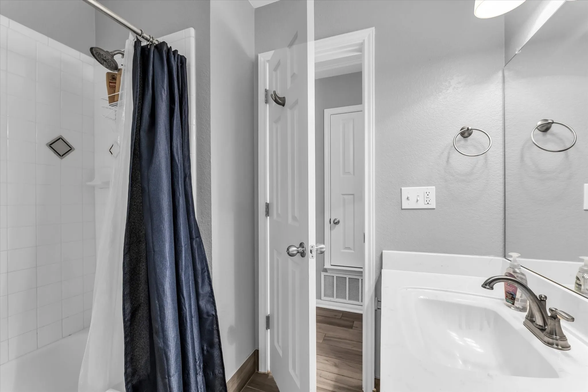 Bathroom featuring a white vanity with a sink, brushed nickel faucet, faux wood-finish flooring, and light gray walls