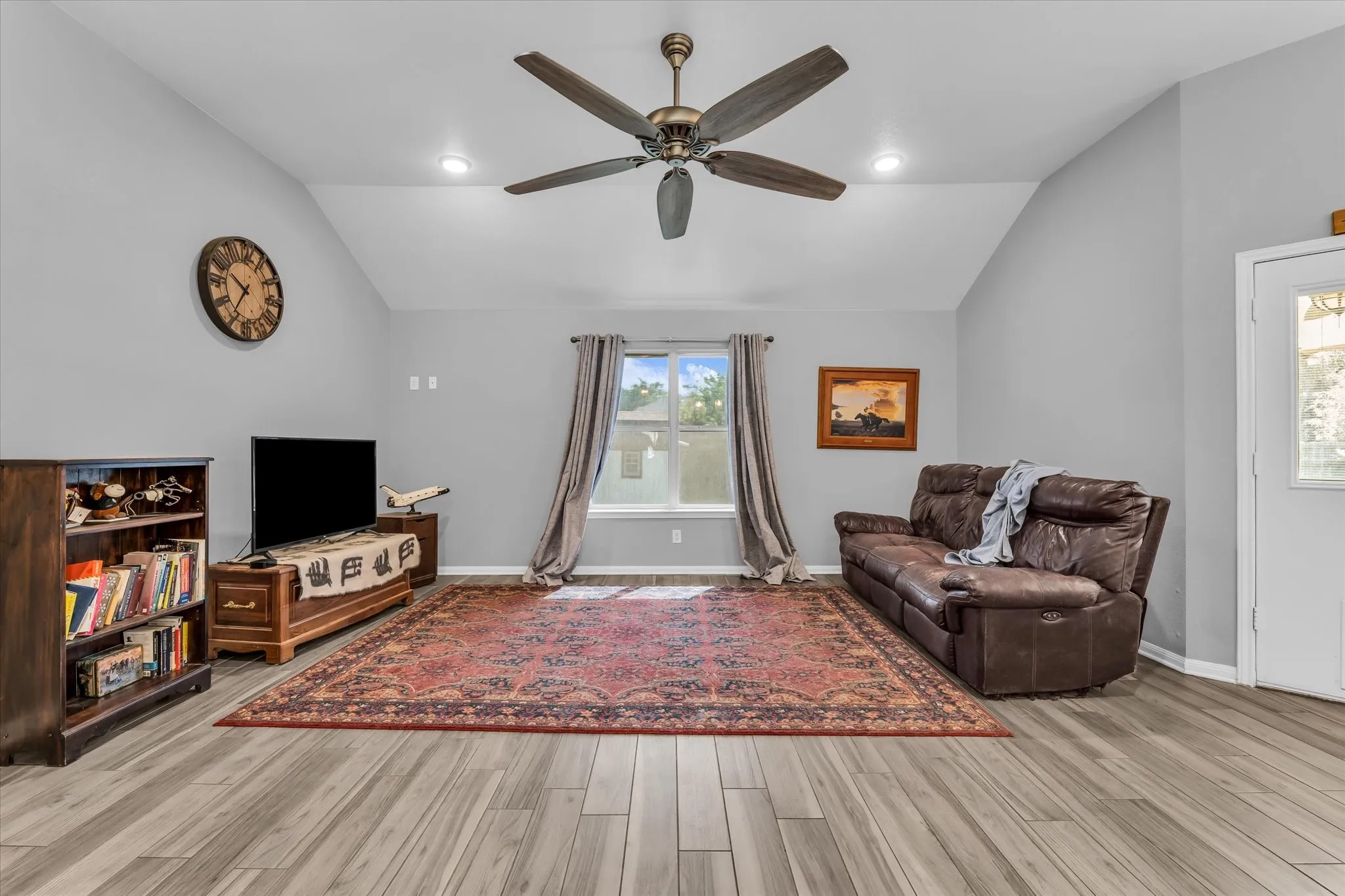 Spacious living area featuring vaulted ceilings, recessed lighting, and wood-finish flooring
