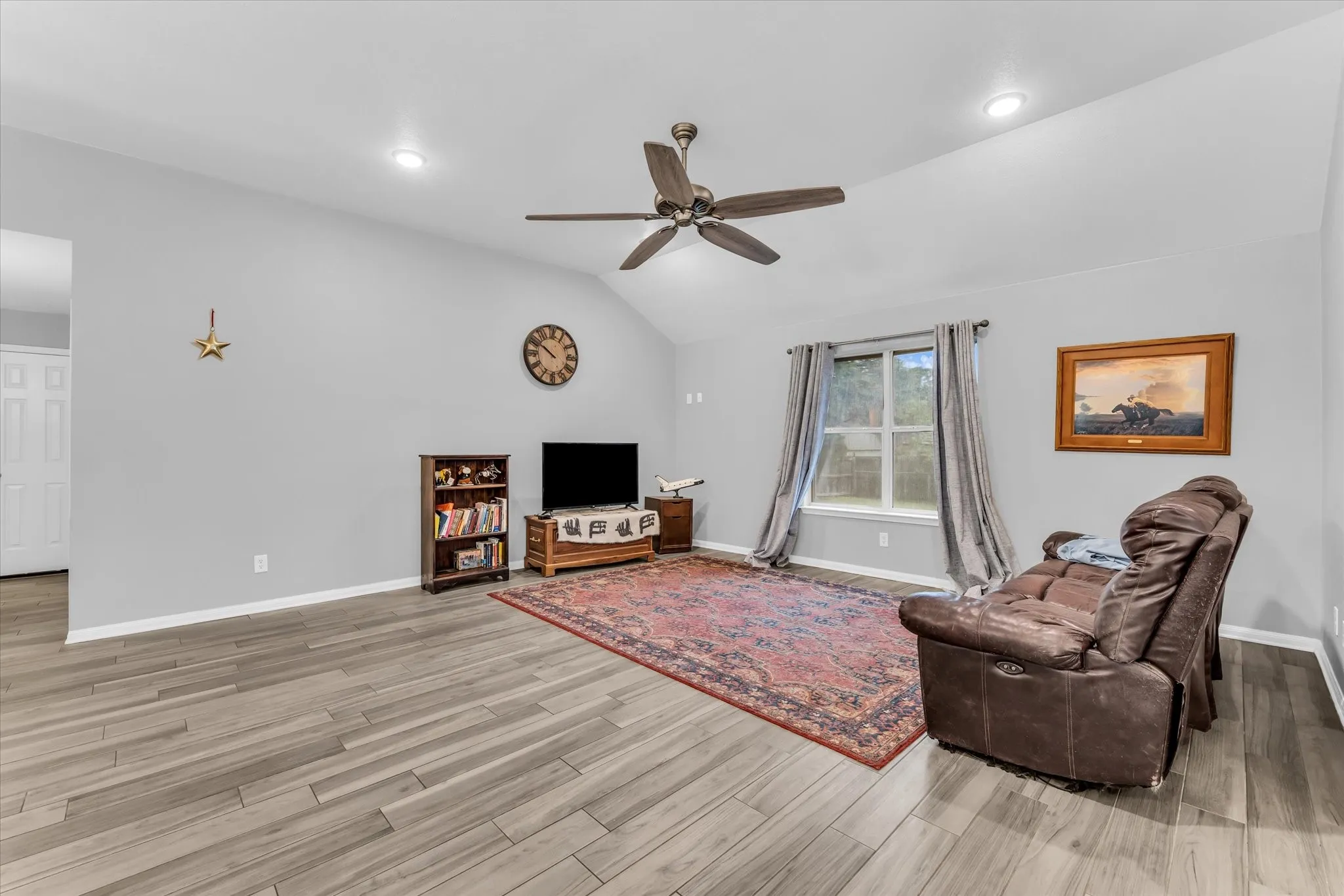 Spacious room featuring a ceiling fan, two windows.