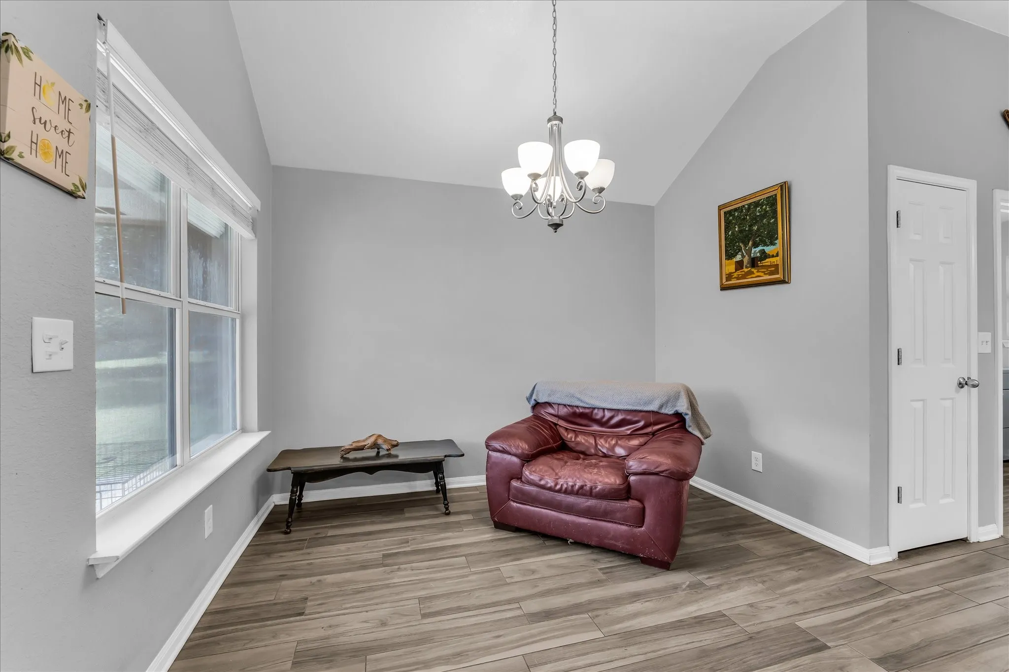 Room featuring wood-finish flooring, a window, and a chandelier light fixture. Dining area is used as a sitting area currently