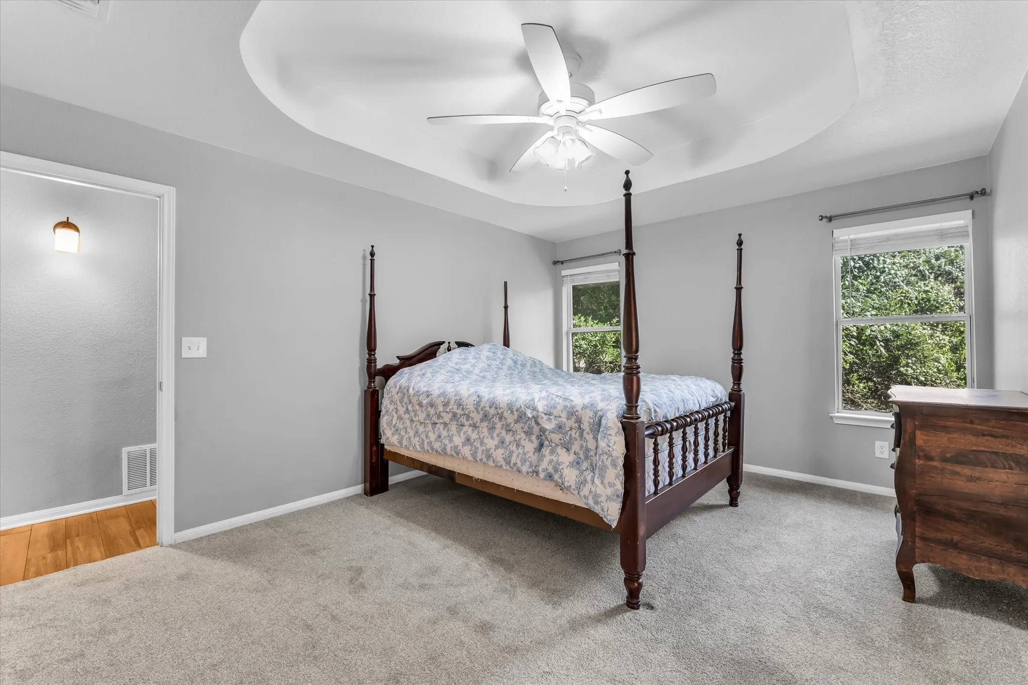Carpeted bedroom featuring a ceiling fan and two windows.