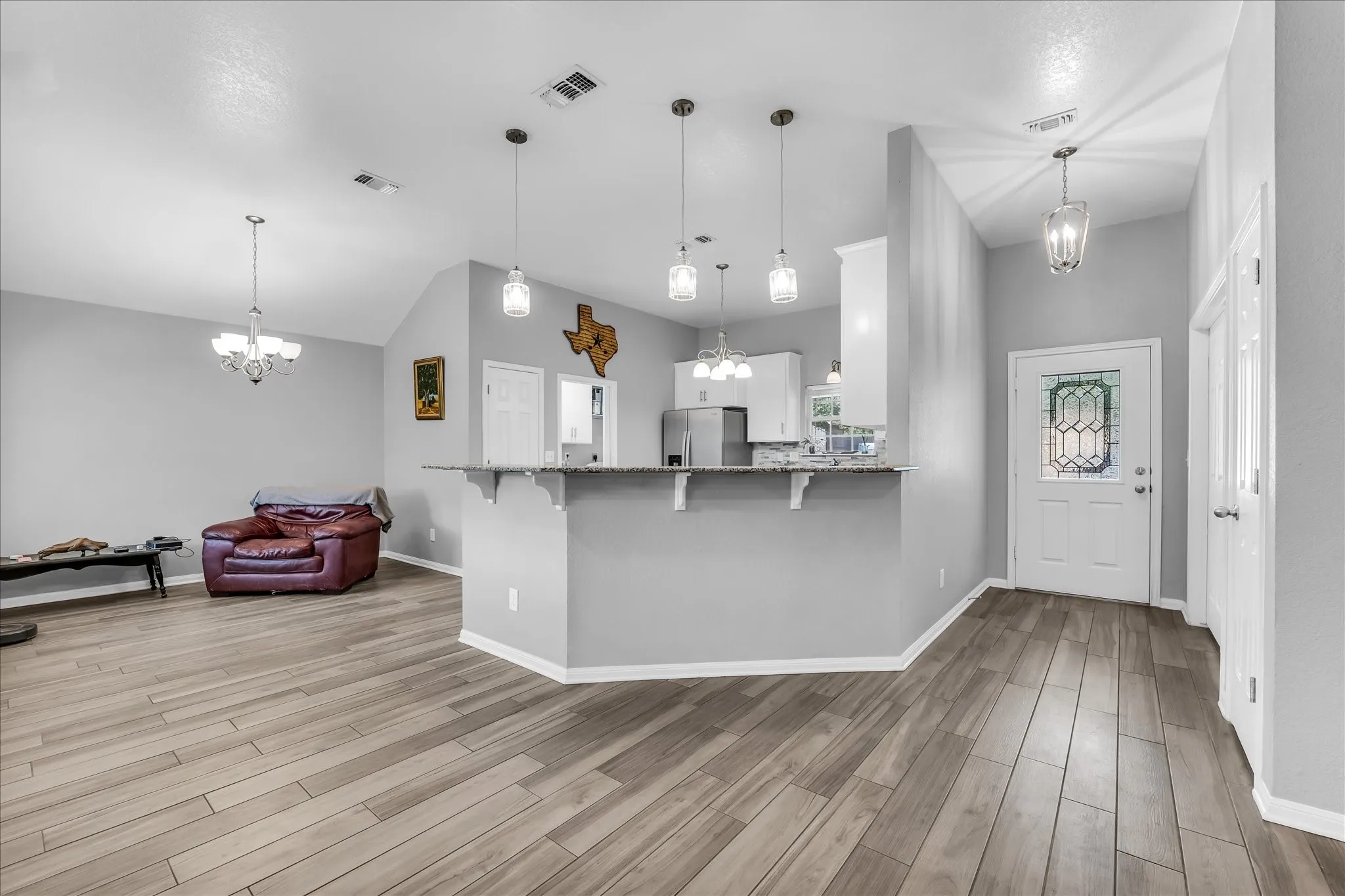 Open-concept living and dining area featuring wood-finish flooring and decorative lighting