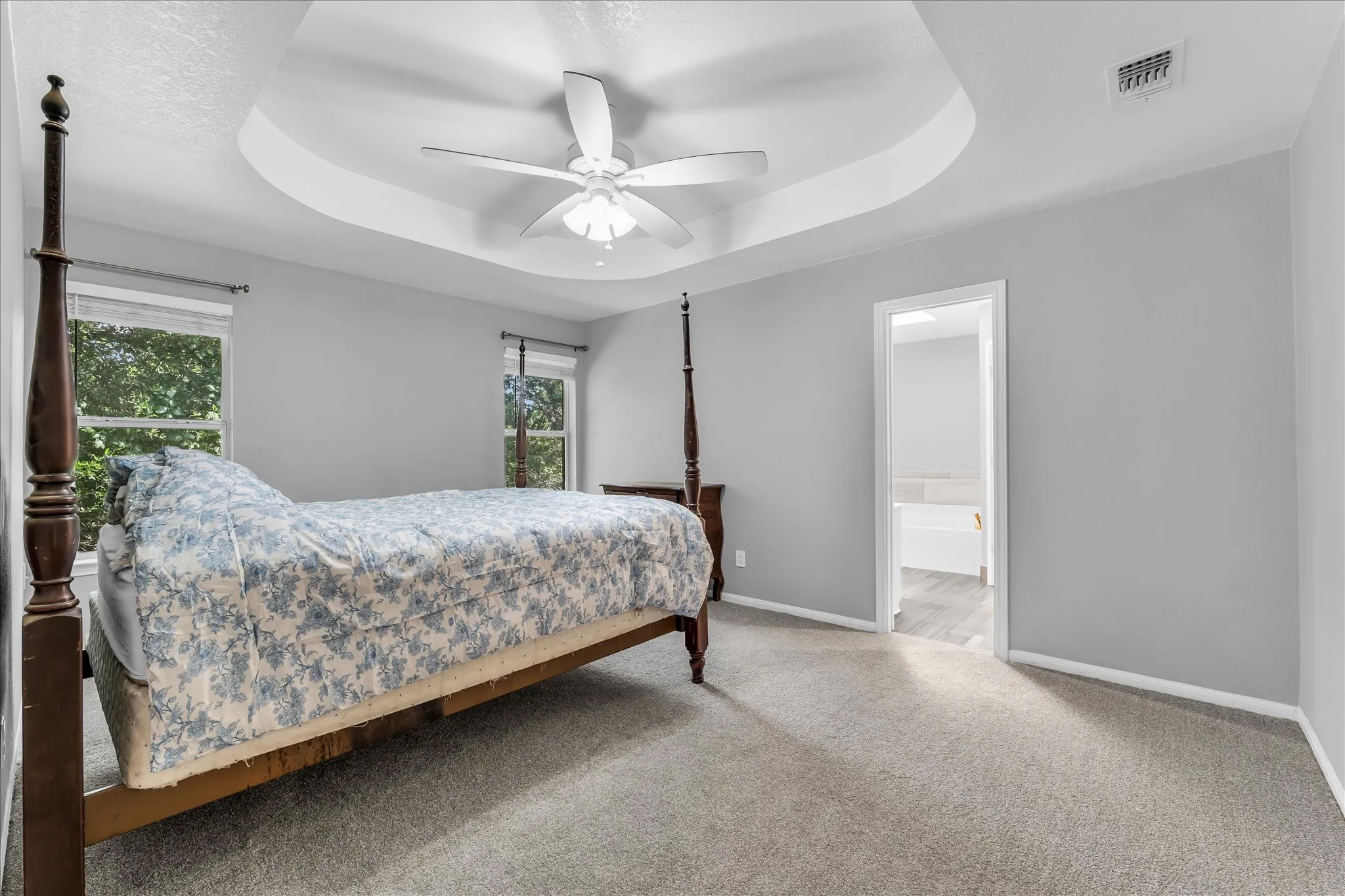 Carpeted bedroom featuring a ceiling fan and two windows.