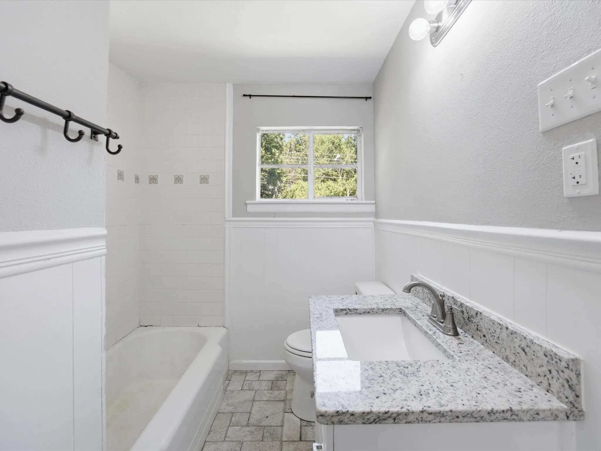 Bathroom featuring a single vanity with a granite countertop, undermount sink, and brushed nickel faucet