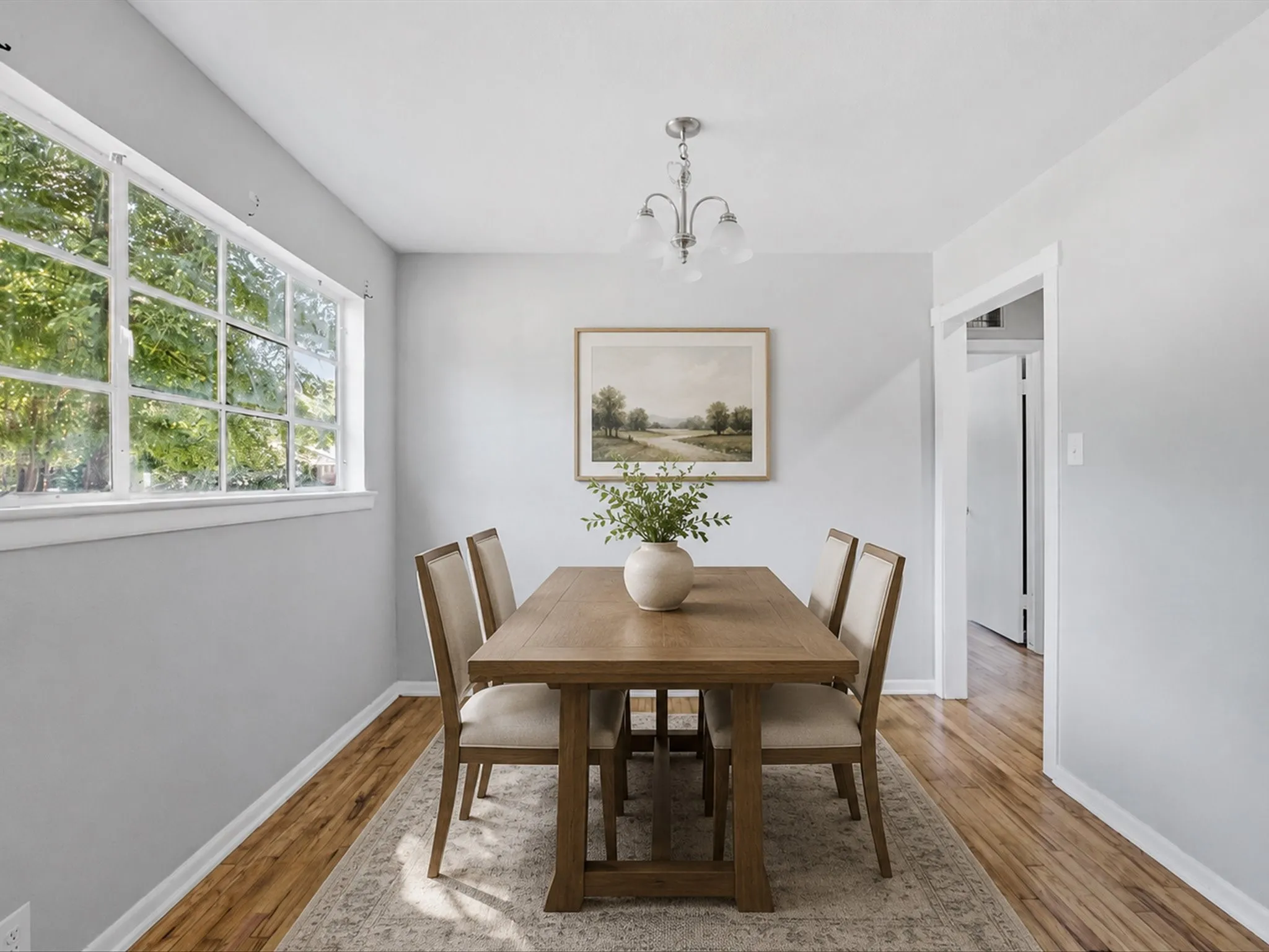 Virtually Staged Dining area featuring wood-finish flooring, light gray walls, and a multi-pane window