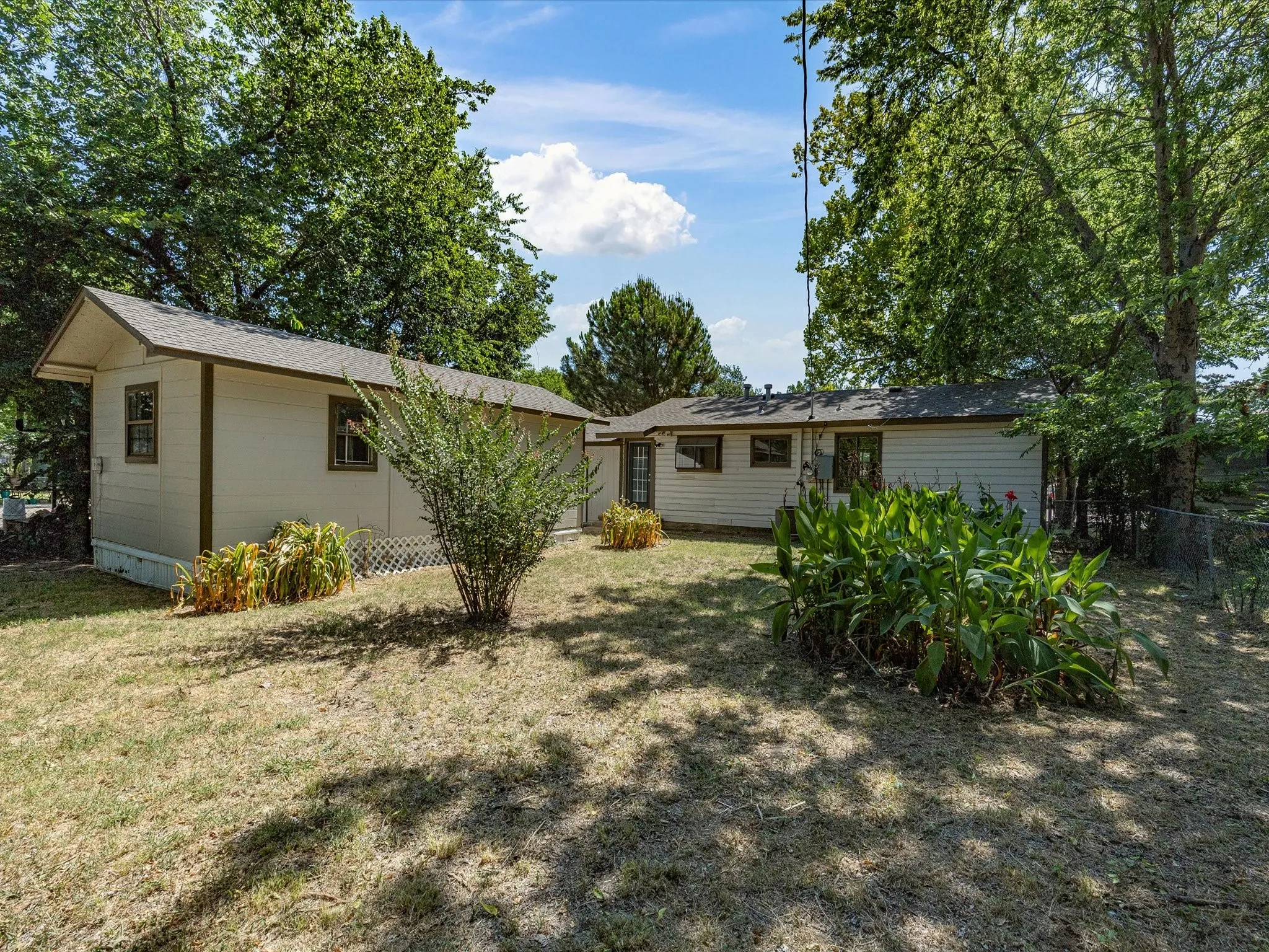 Rear exterior showcasing two structures with beige siding and brown trim