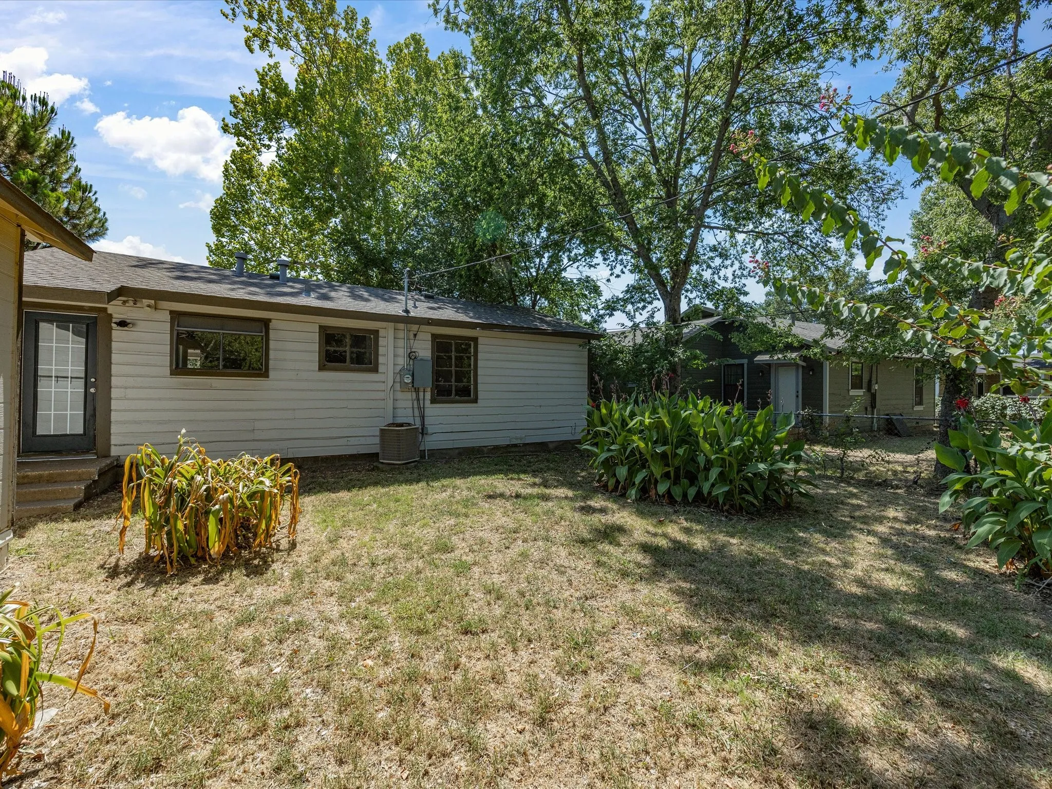Rear exterior with horizontal siding, dark trim windows, and a black-framed glass door with muntins