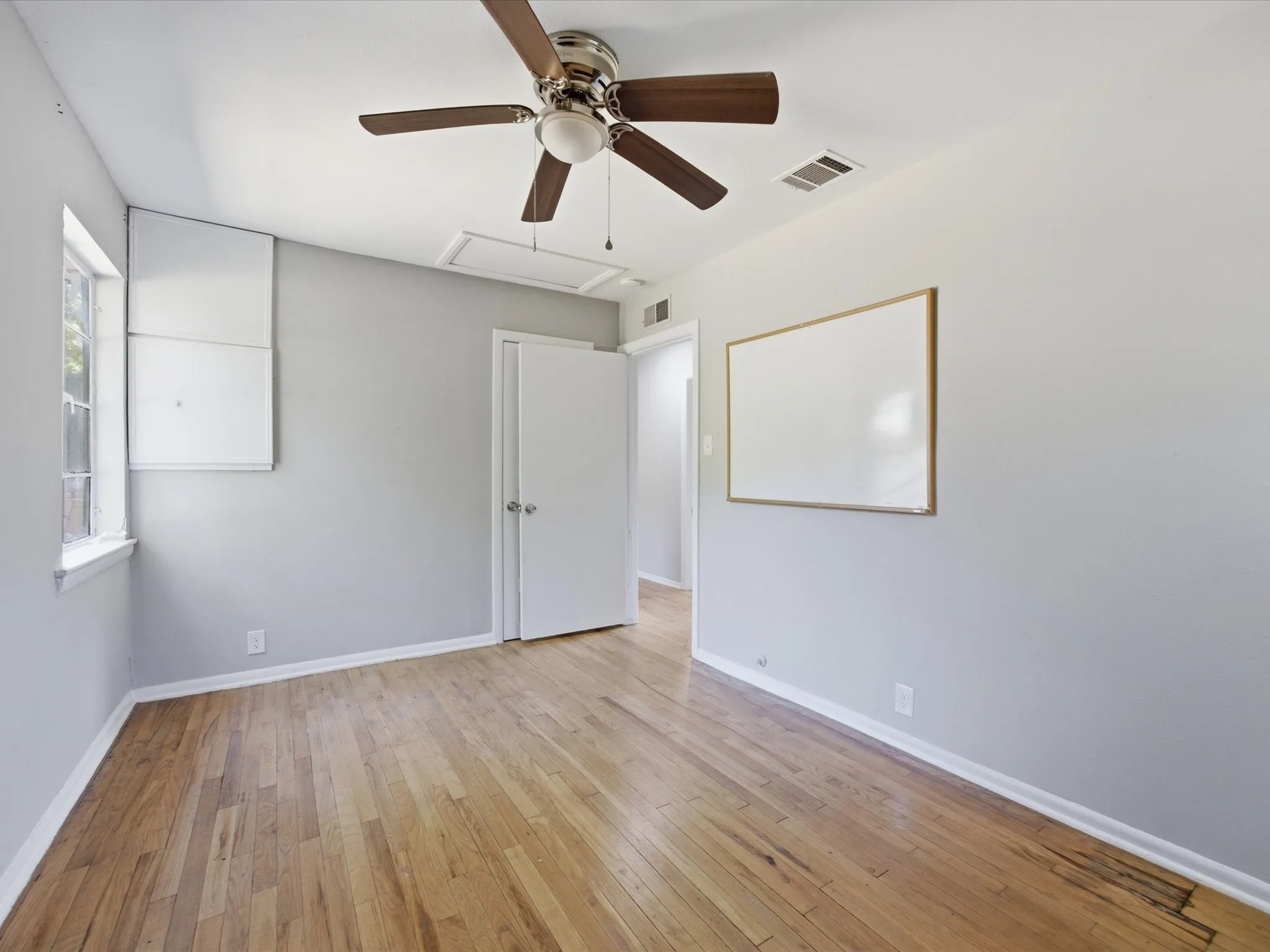 Bright bedroom featuring wood-finish flooring and a ceiling fan with integrated lighting