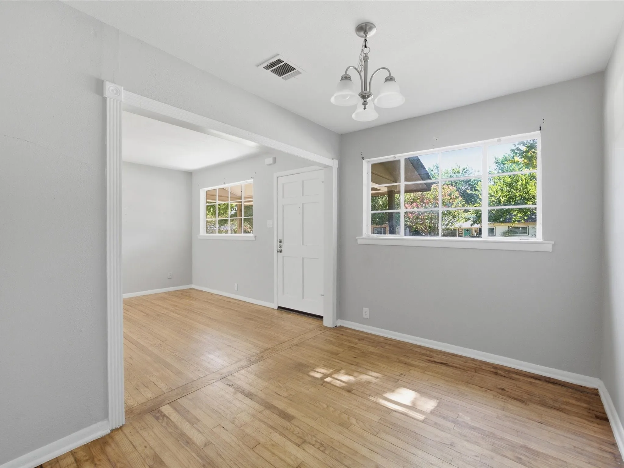 Bright interior space featuring wood-finish flooring, light grey walls, and a multi-pane window