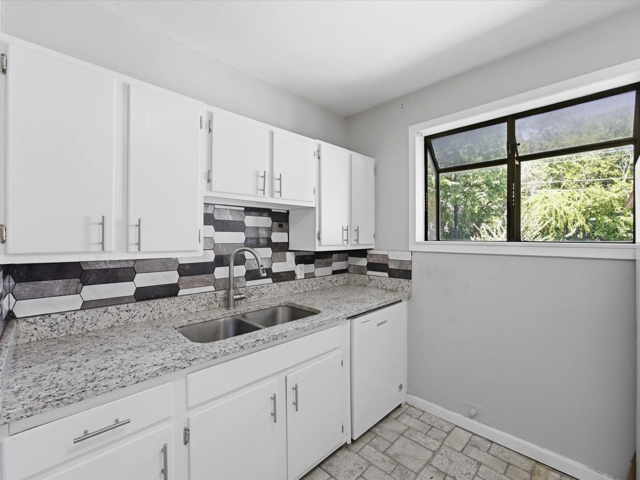 Kitchen featuring white cabinetry, a dual basin stainless steel sink with a high-arc faucet, granite-patterned countertops, and a decorative tile backsplash