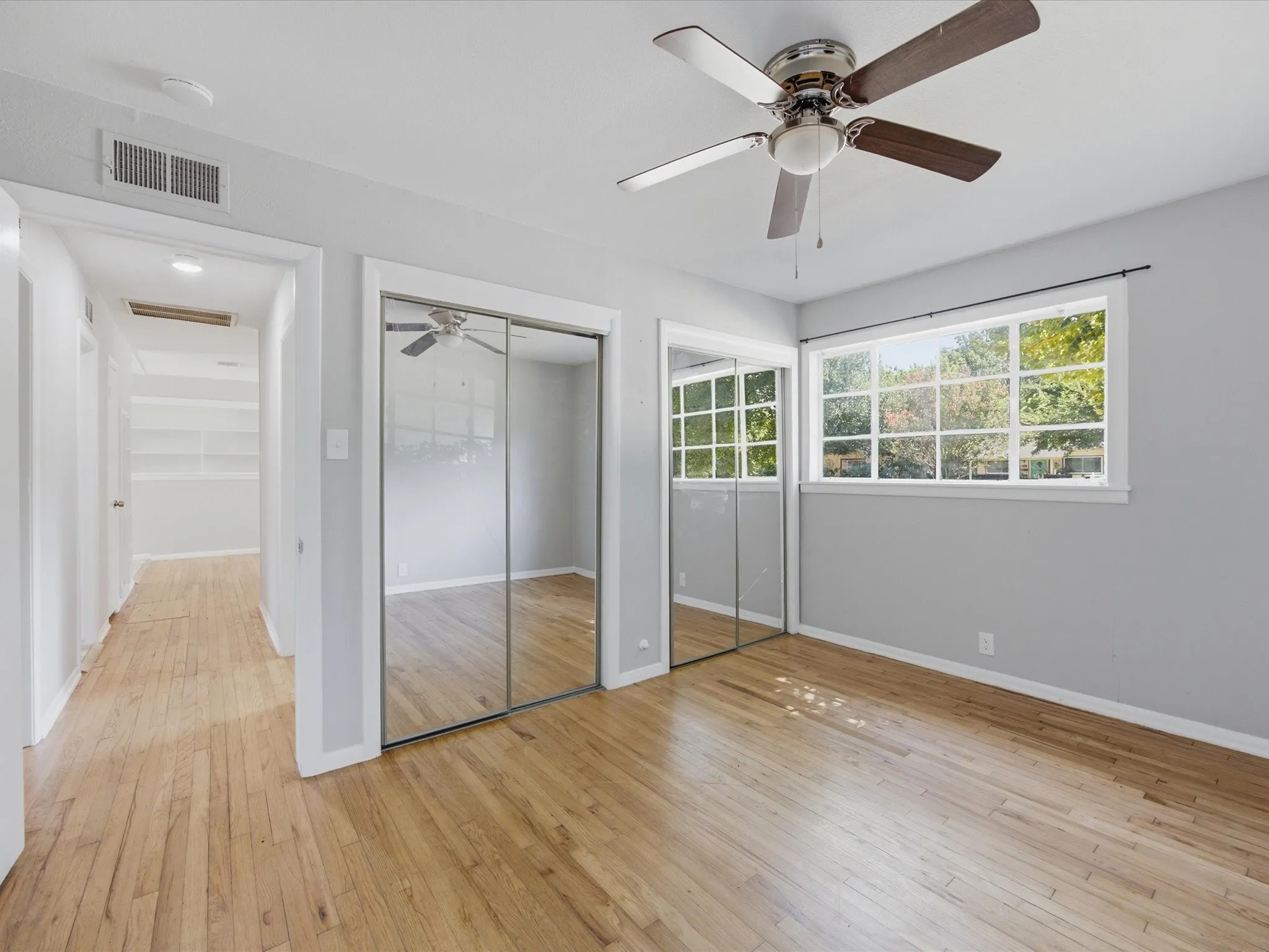 Bright Primary bedroom featuring wood-finish flooring and a ceiling fan with integrated lighting