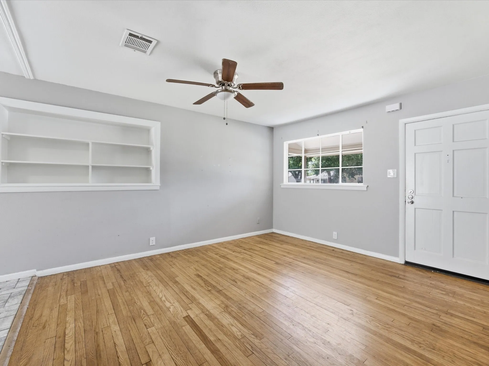 Bright interior living room featuring wood-finish flooring adjacent to Dining & Kitchen