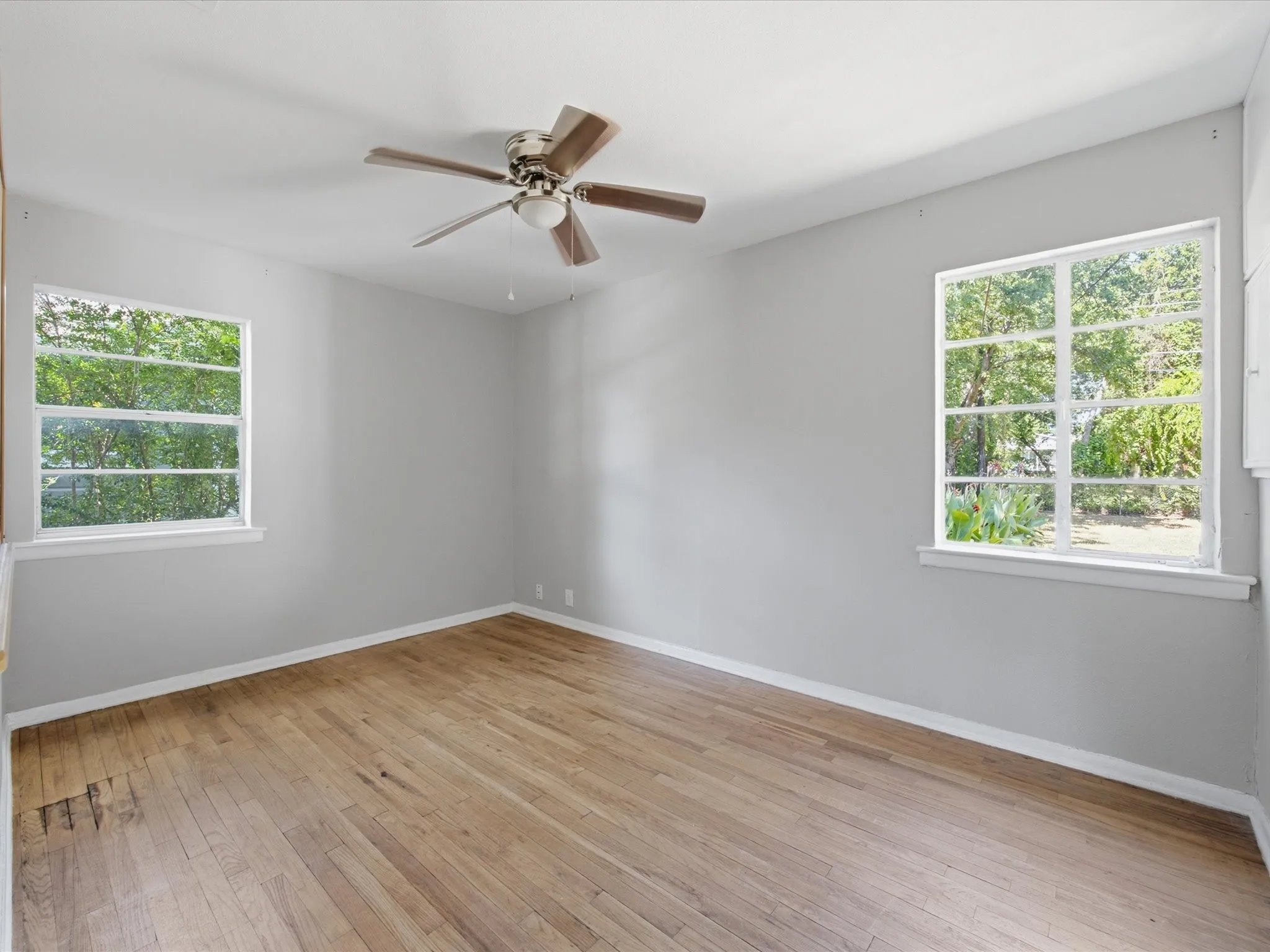 Hardwood flooring throughout this bedroom featuring a ceiling fan with integrated lighting