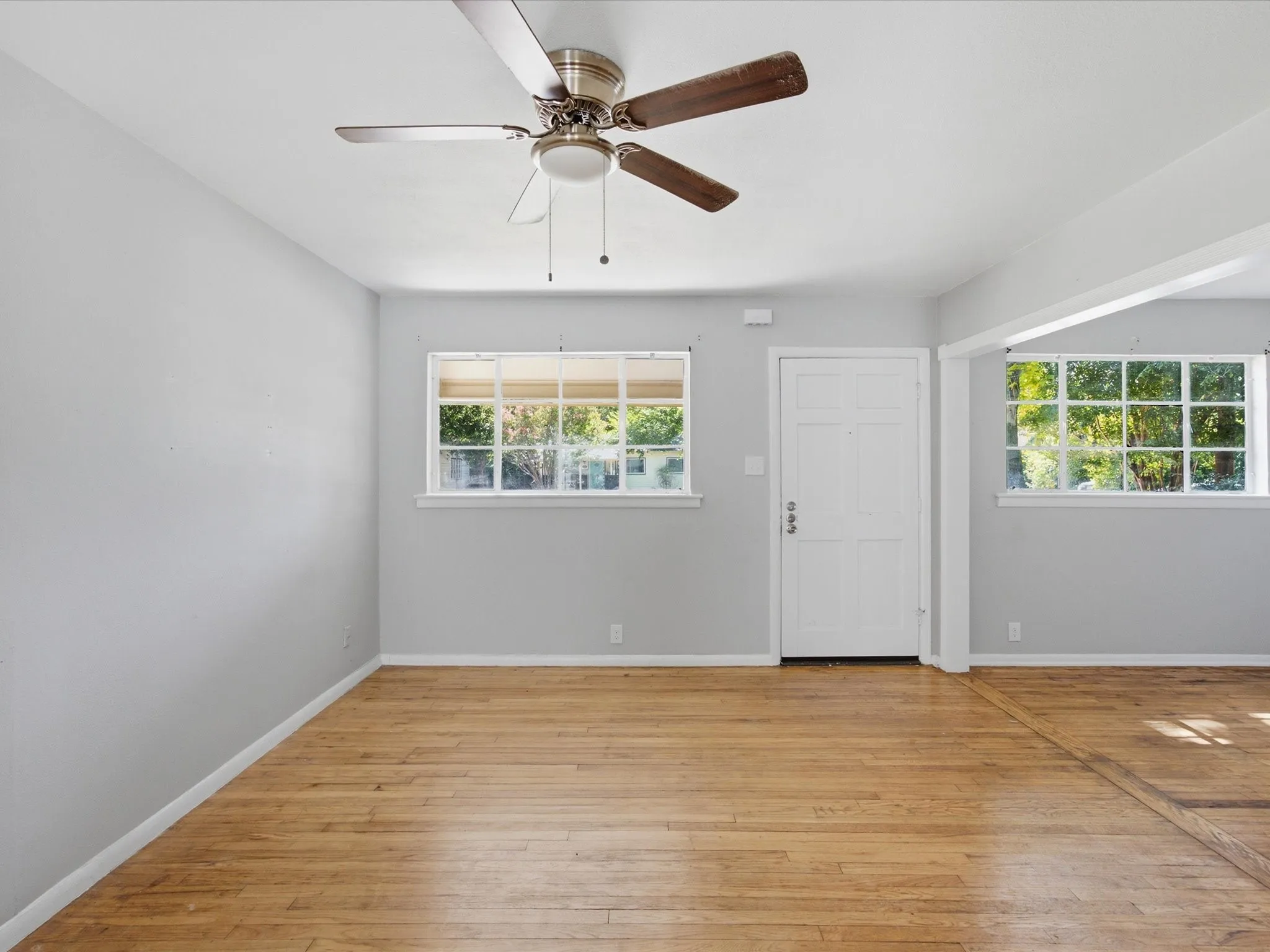 Bright interior living room featuring wood-finish flooring adjacent to Dining & Kitchen