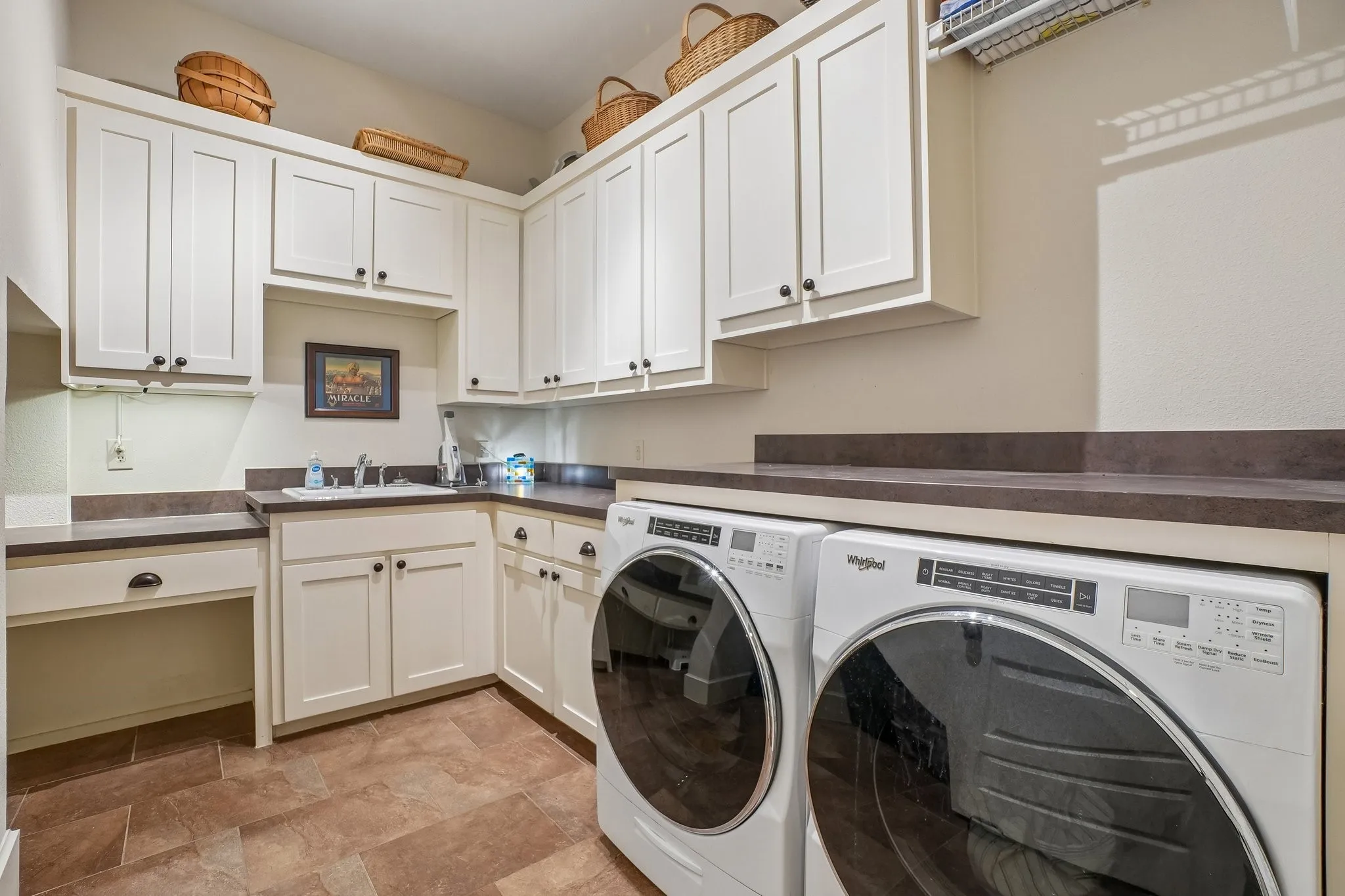 Laundry area featuring white cabinetry, integrated sink, and ample countertop space