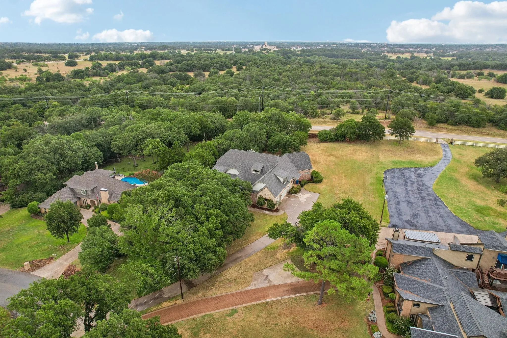 Expansive property featuring a large residence, a private swimming pool, mature trees, and an extended driveway