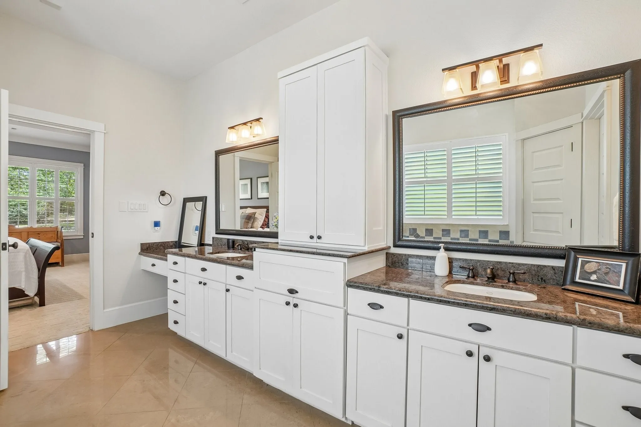 Double vanity with white cabinetry and dark countertops