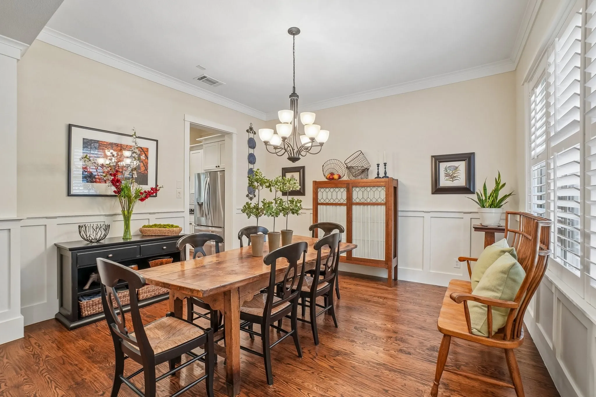 Dining area featuring wood-finish flooring, wainscoting, crown molding, and a multi-bulb chandelier