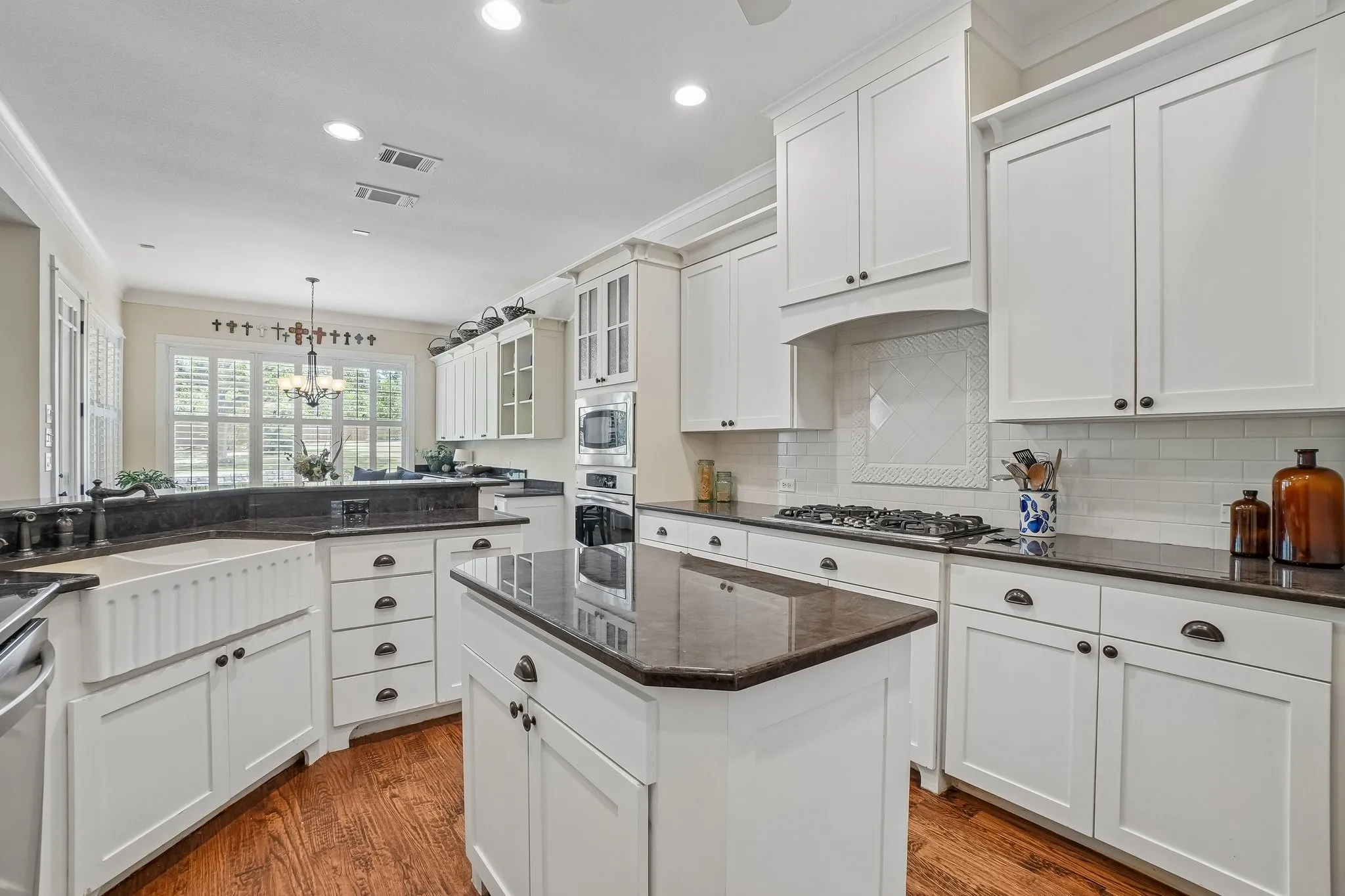 White shaker cabinetry featuring dark countertops and a farmhouse-style sink