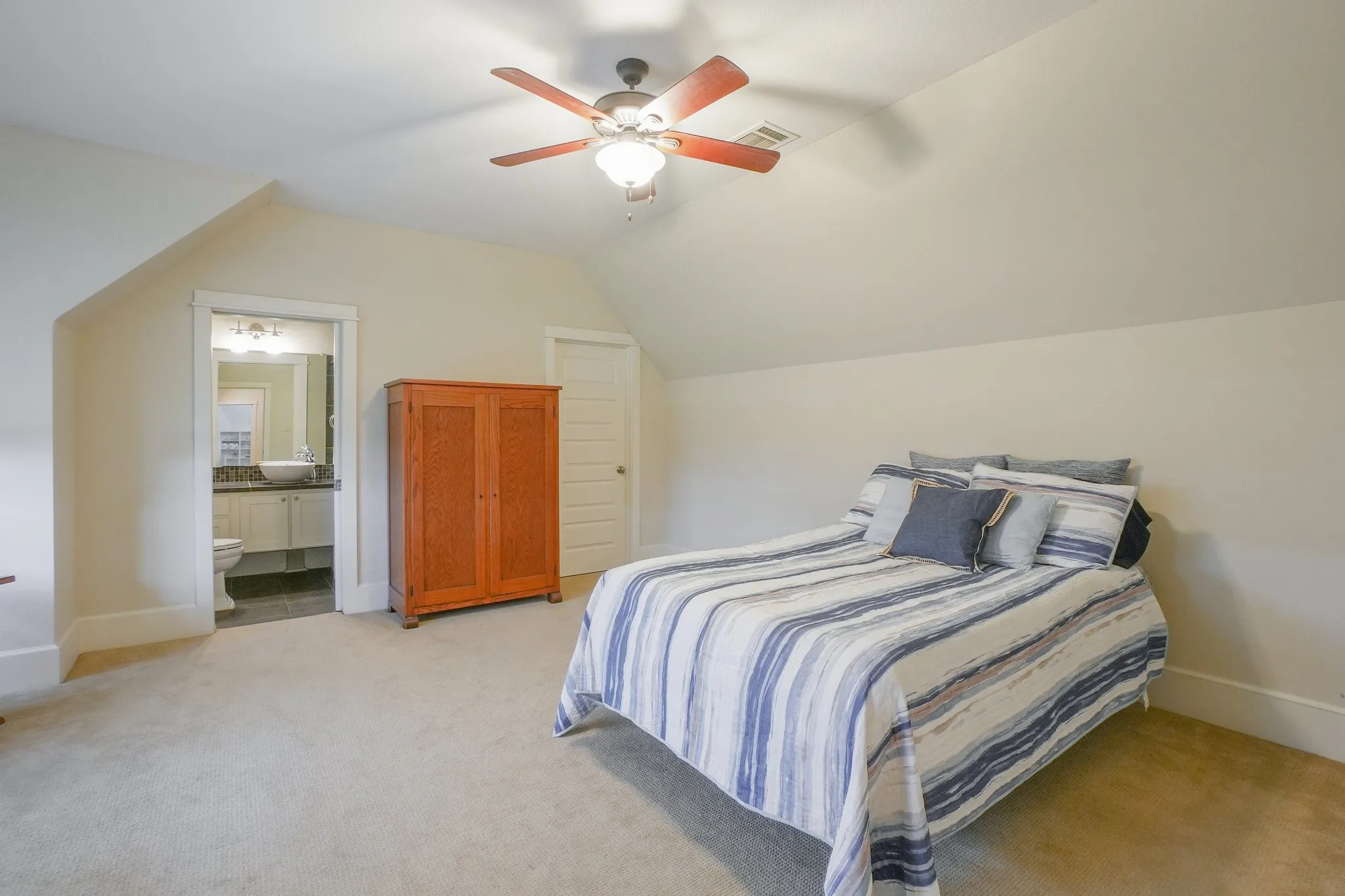 Carpeted room with sloped ceilings and a ceiling fan