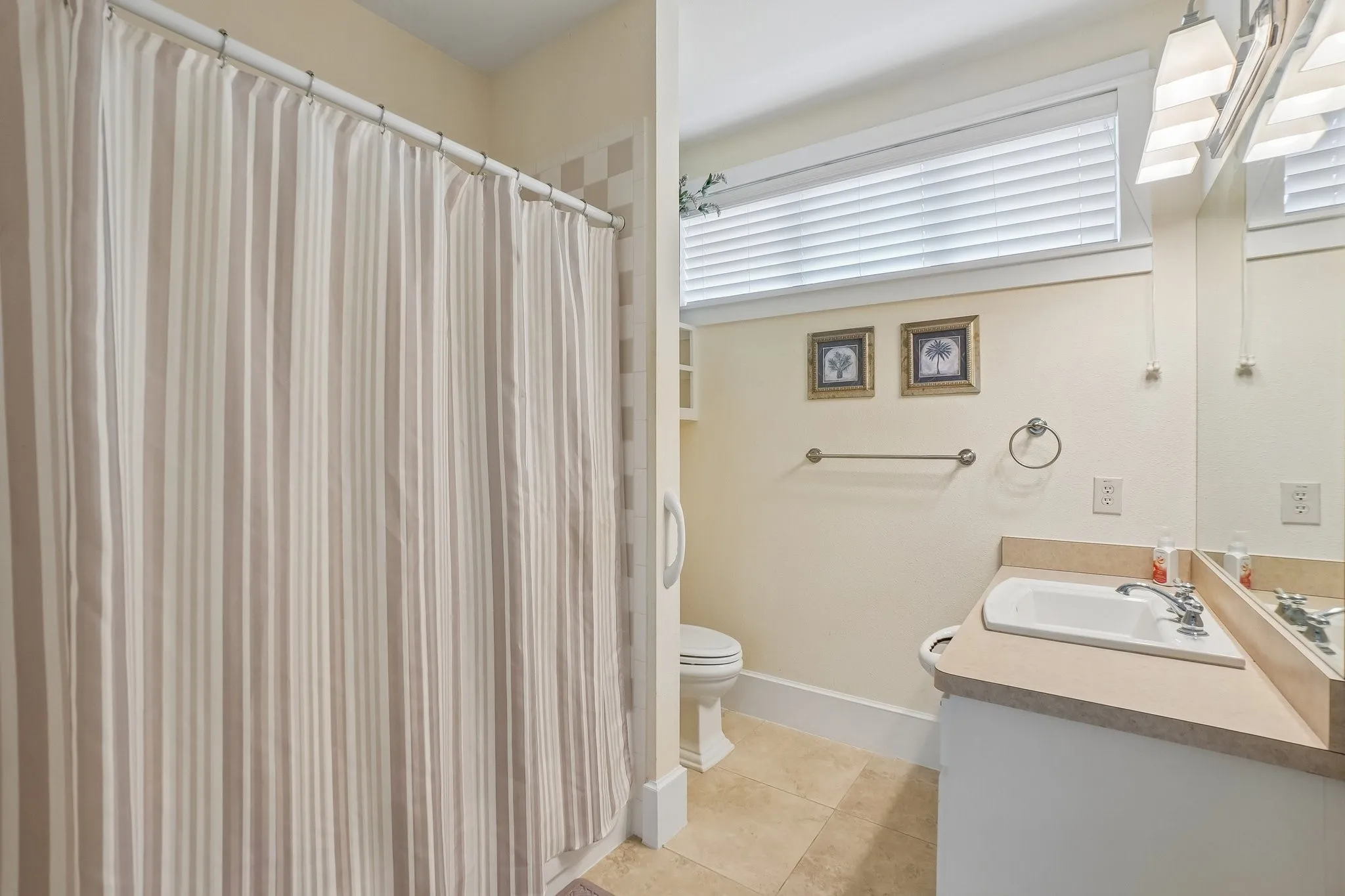 Bathroom featuring a shower with striped curtain, tile flooring, vanity with integrated sink, window with blinds, and wall-mounted mirror