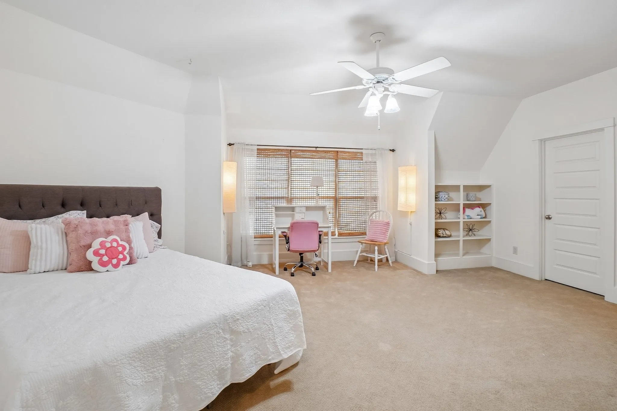 Spacious room featuring carpeting, a ceiling fan with light fixture, a large window with blinds, and built-in shelving