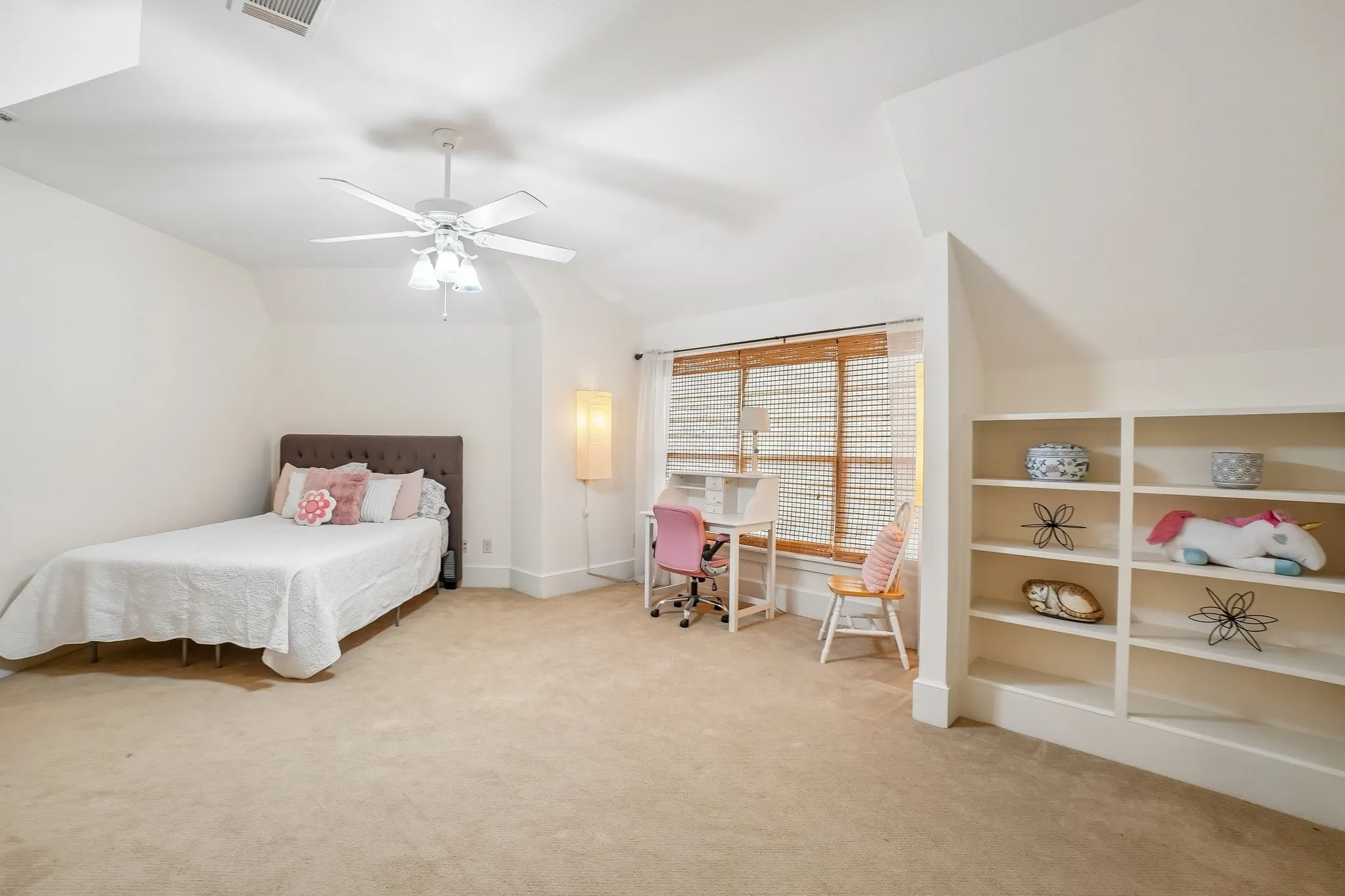Carpeted room with a ceiling fan, window with blinds, and built-in shelving