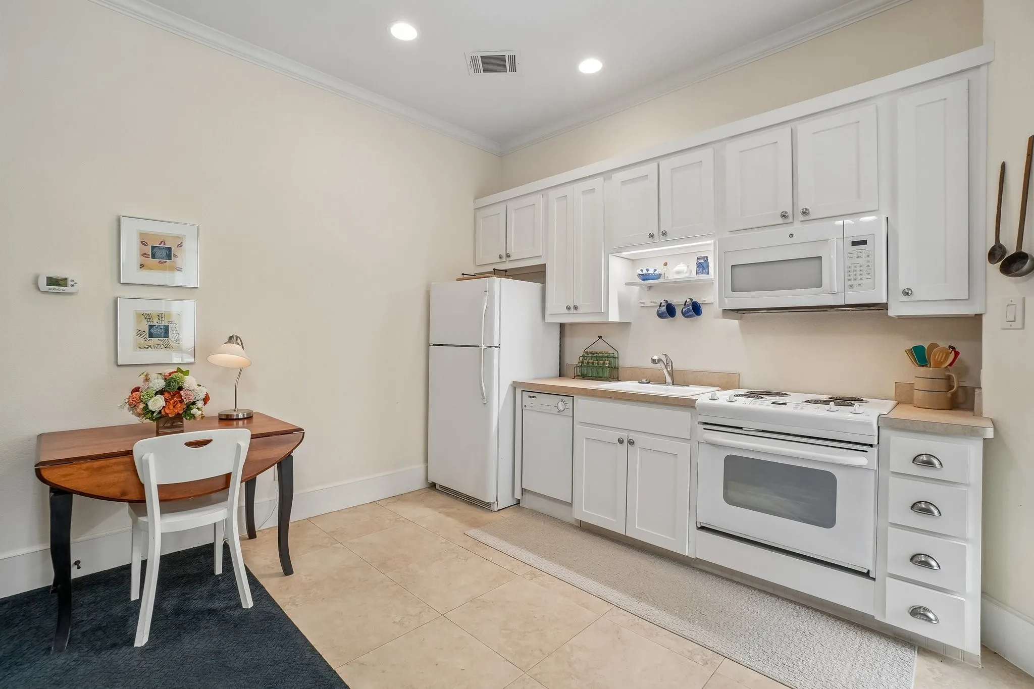 Efficient kitchen featuring white cabinetry, integrated microwave, built-in dishwasher, and a full-size refrigerator