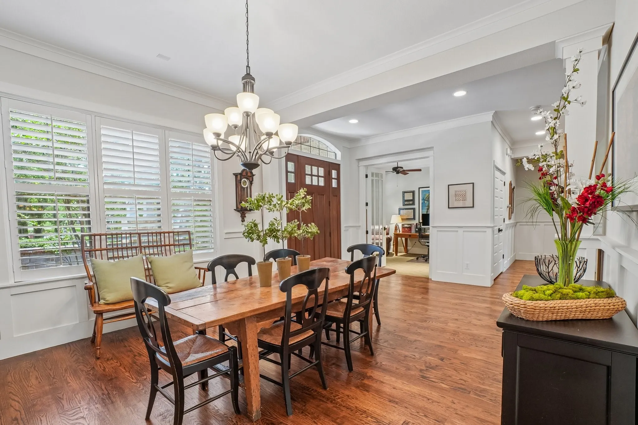 Dining area featuring wood-finish flooring, white wainscoting, an ornate chandelier, and plantation shutters