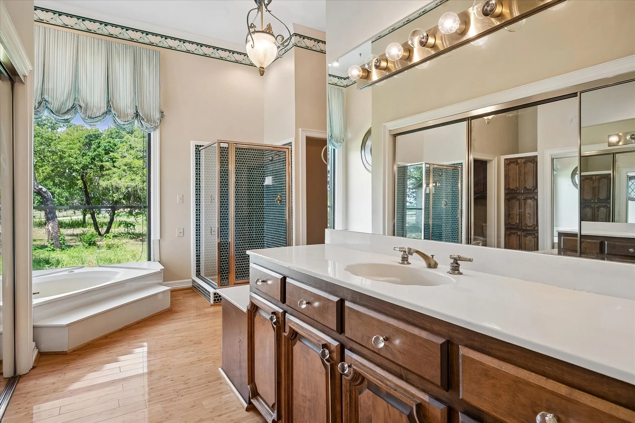 Bathroom featuring a built-in corner soaking tub, a stand-alone shower enclosure, and wood-finish flooring