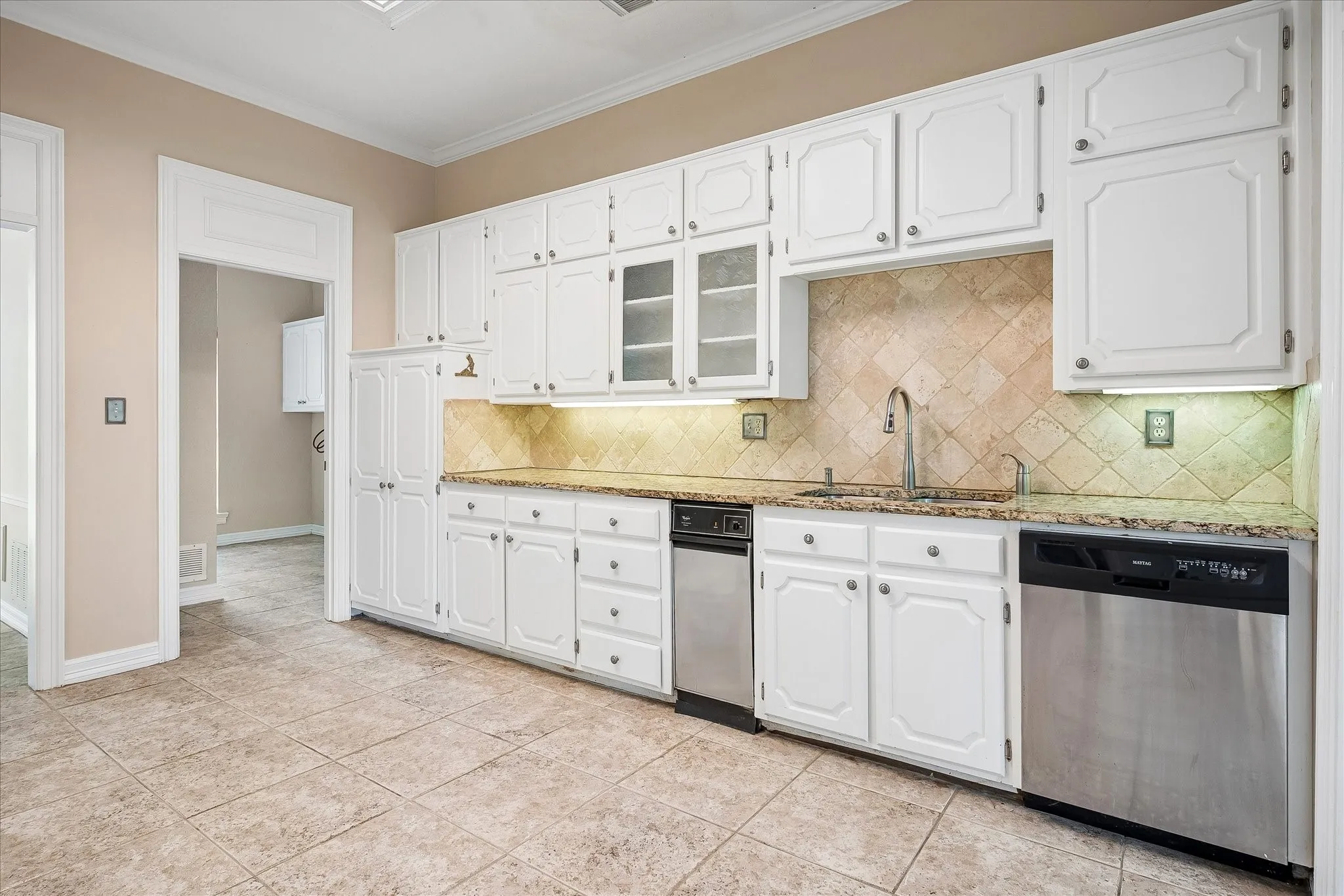 Kitchen featuring white cabinetry with glass-front accents, granite countertops, and a tiled backsplash