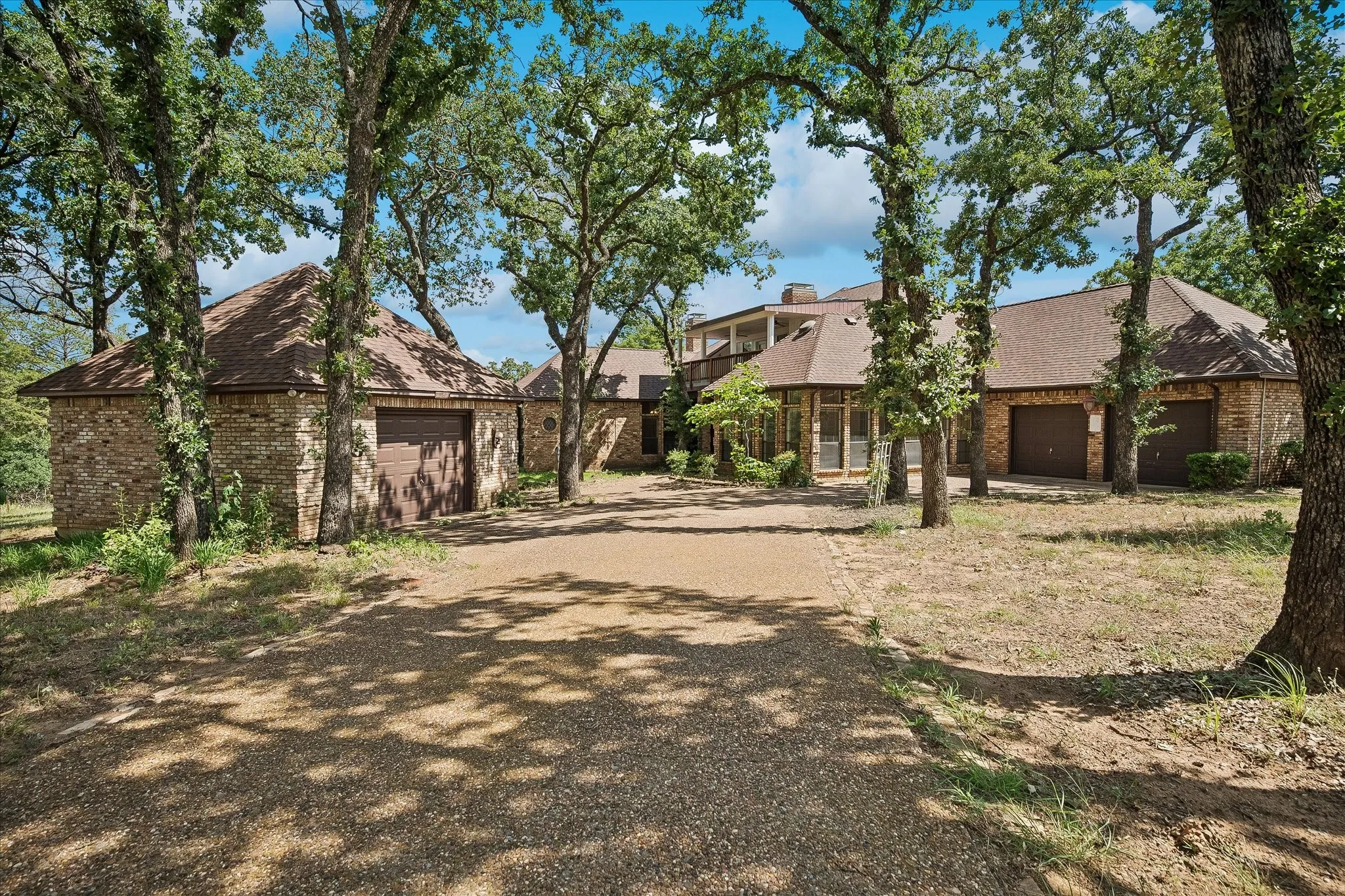 Stone-clad exterior with multiple garage bays and a gravel driveway