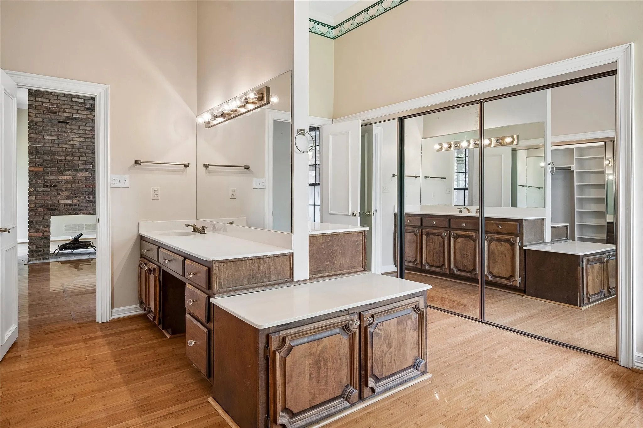 Spacious bathroom featuring wood-finish flooring, a dual vanity with integrated sinks, and ample countertop space