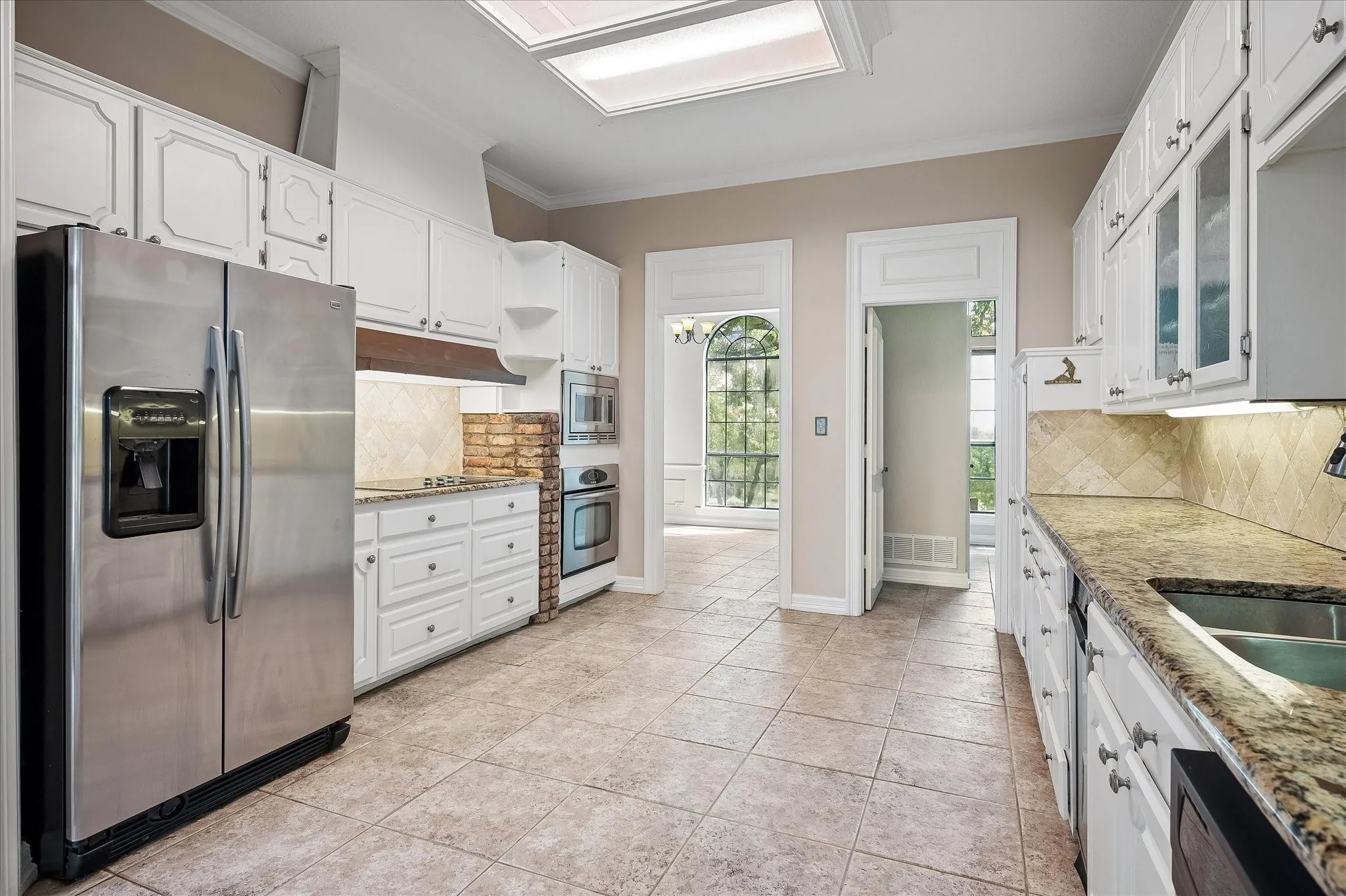 Kitchen featuring white cabinetry, stainless steel appliances, granite countertops, and tile flooring