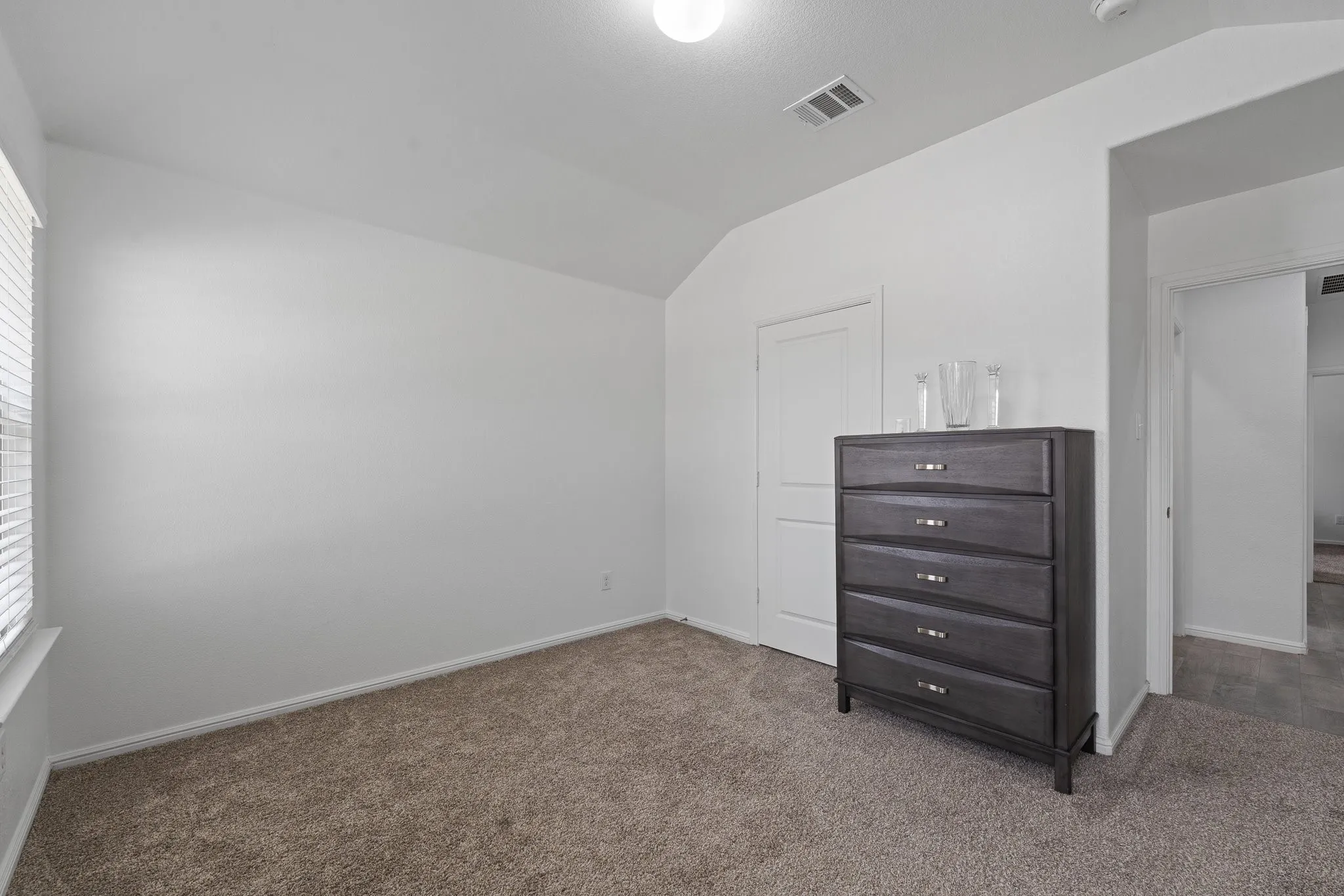 Carpeted interior space featuring neutral wall paint, a window with blinds, and white trim