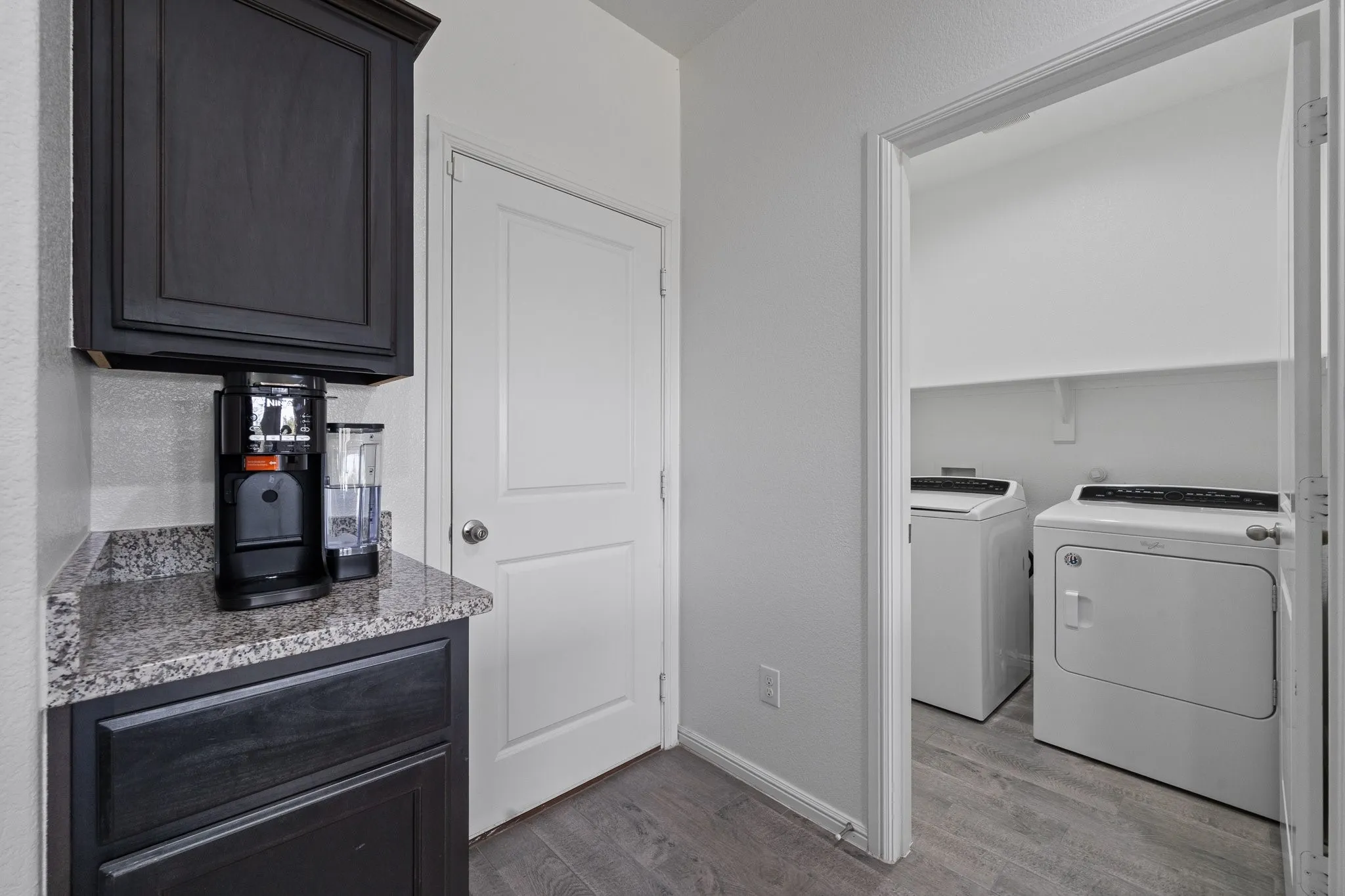 Built-in cabinetry with stone-finish countertop, wood-finish flooring, and dedicated laundry area with shelving